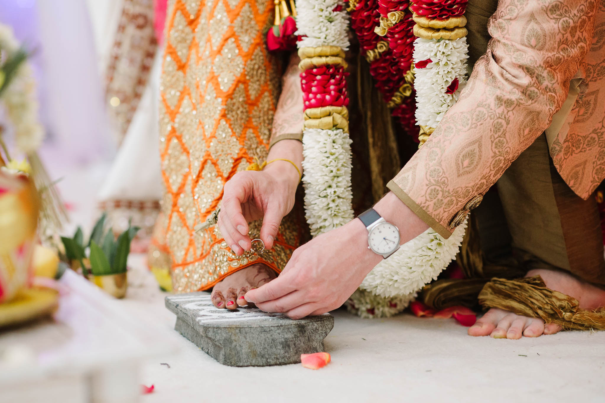 groom putting toe ring on brides foot