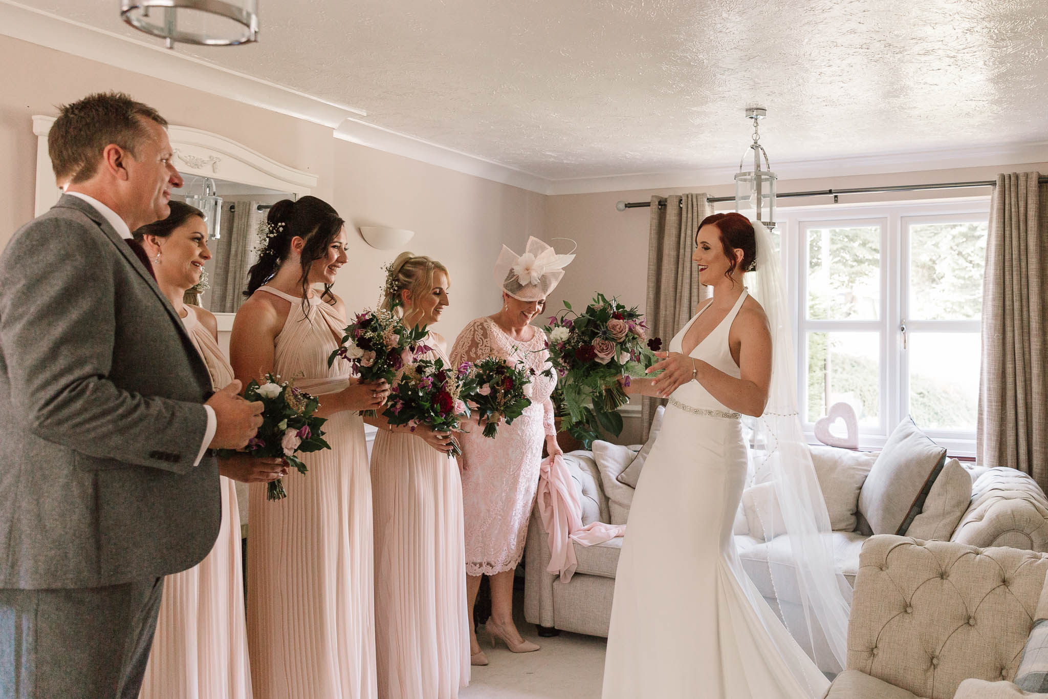 bridesmaids and mum and dad seeing bride in her dress