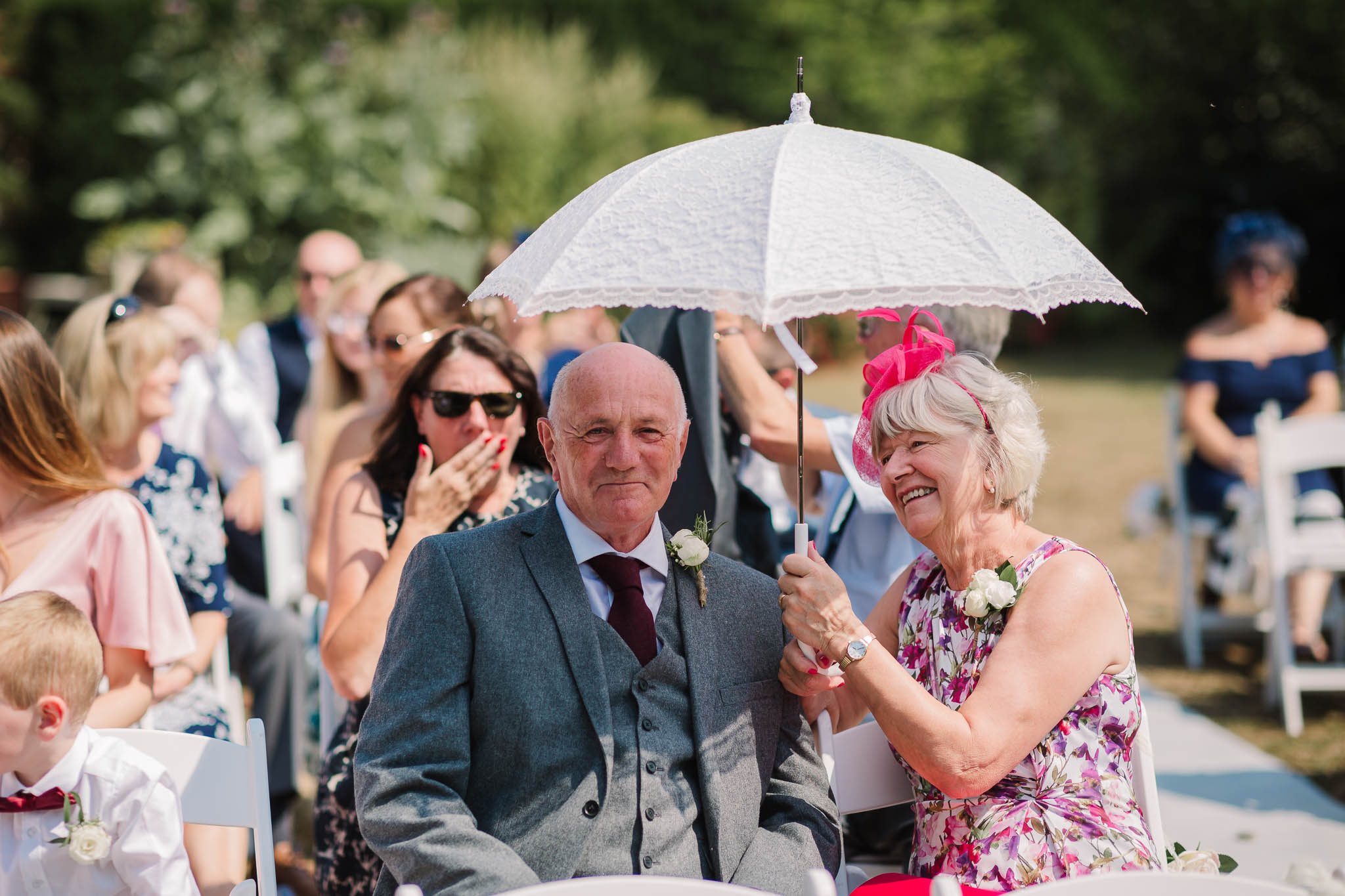 parents with umbrella at sunny summer wedding