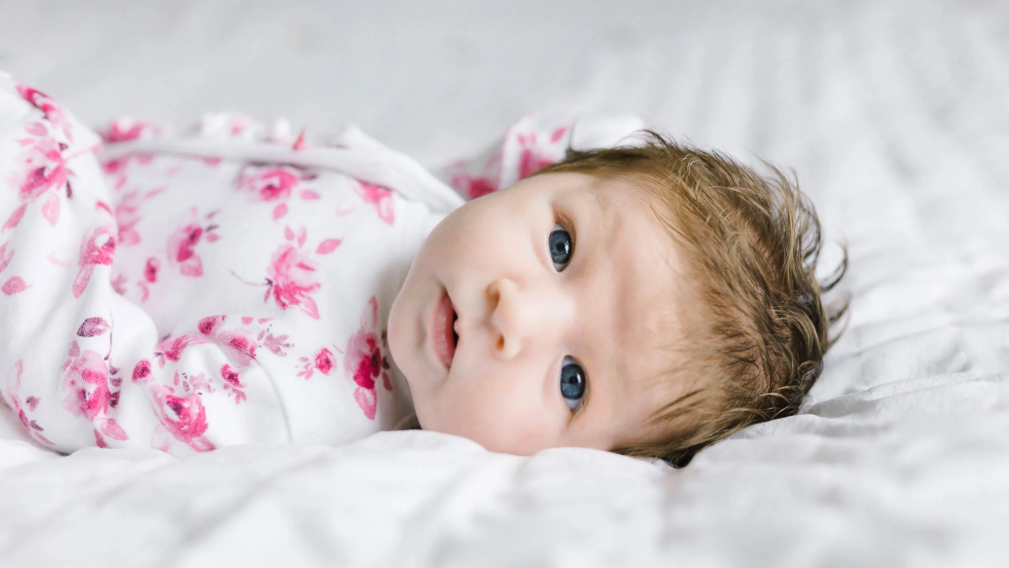 baby girl in pink floral baby grow
