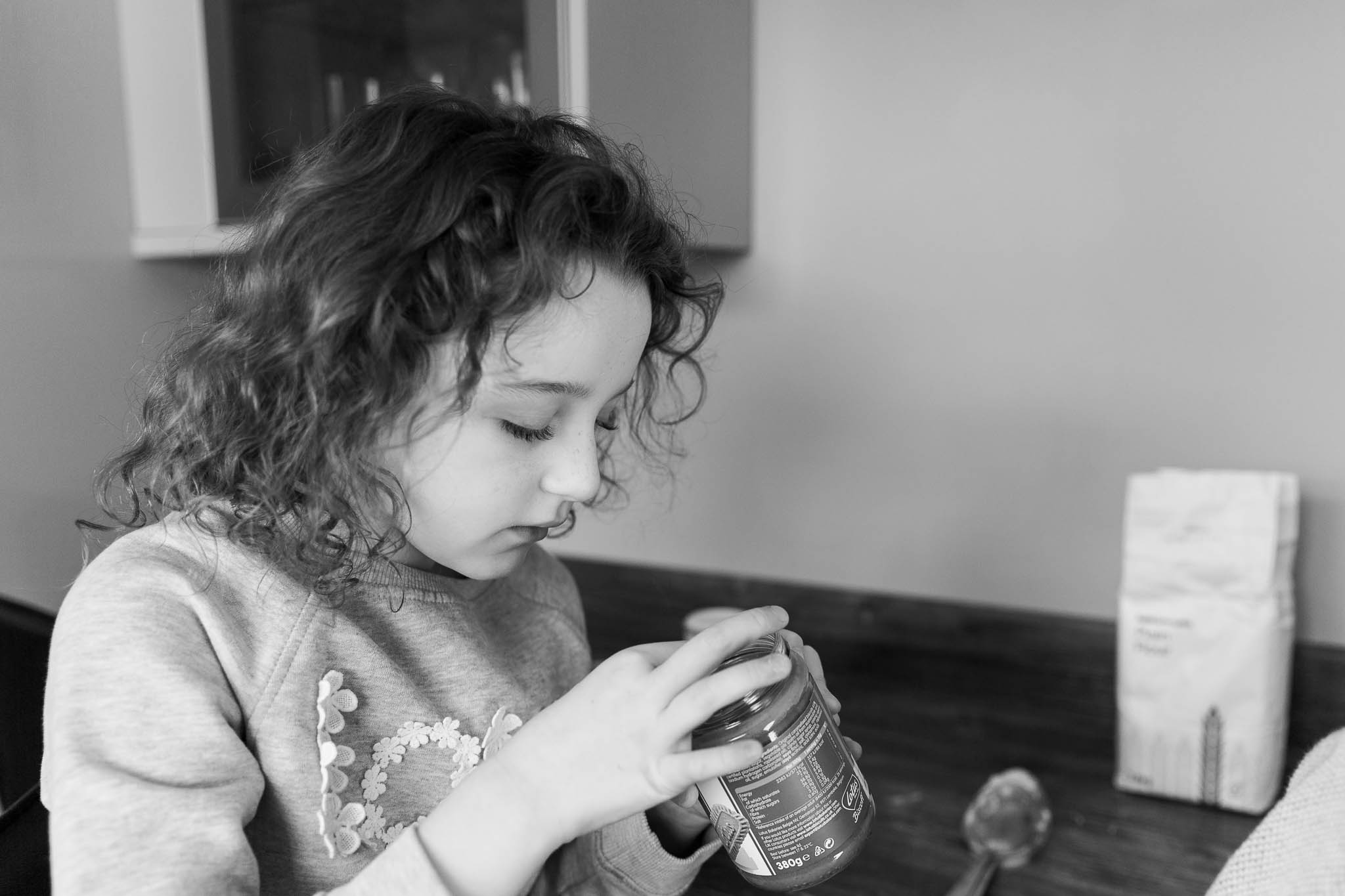 little girl dipping finger into jar