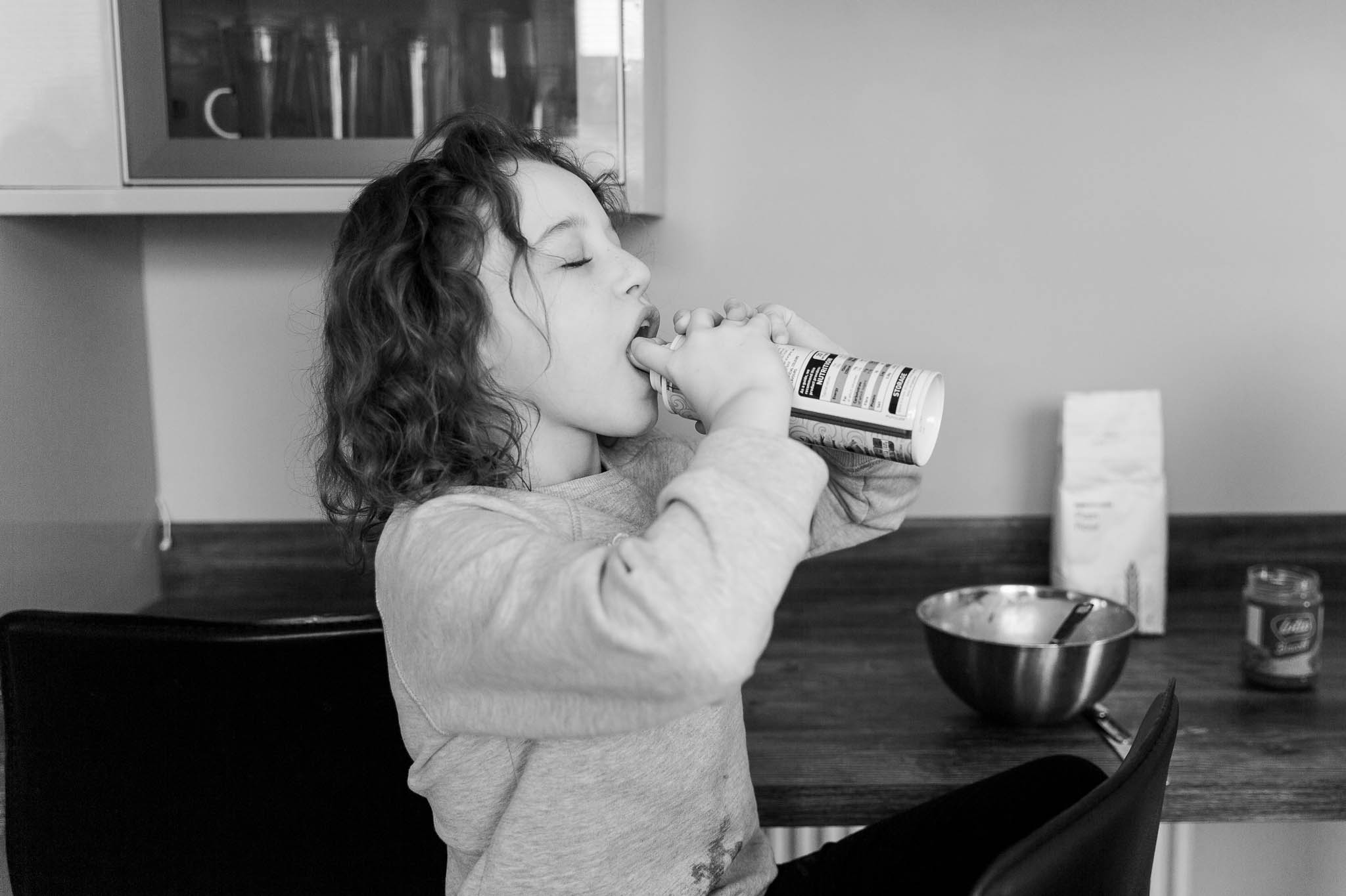 little girl squirting cream into her mouth
