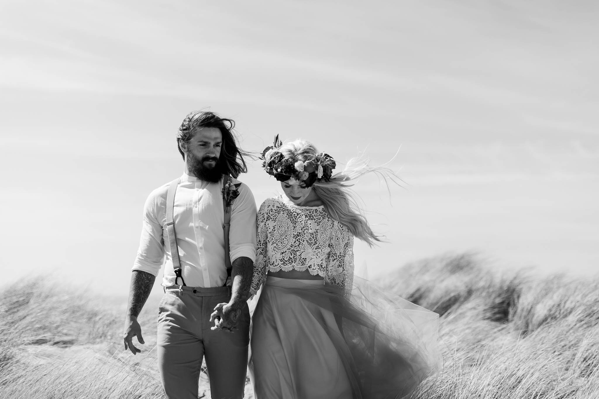bride and groom walking through sand dunes