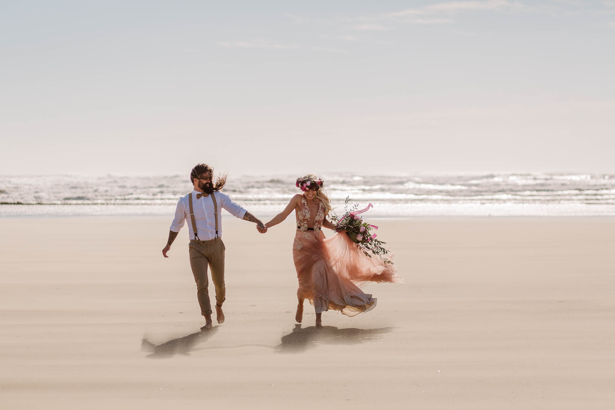 bride and groom running on the beach together