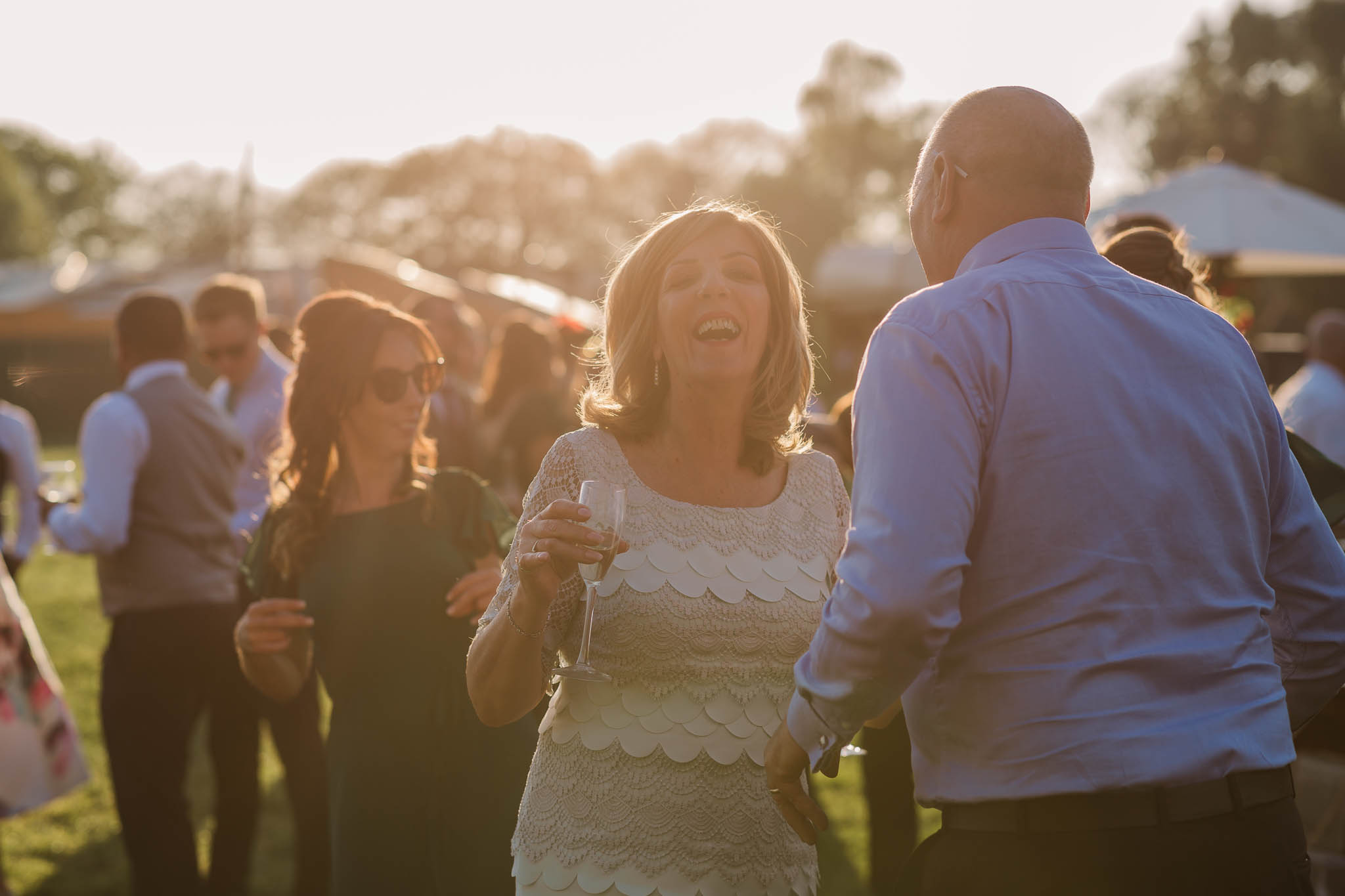wedding guests dancing outside at sunset
