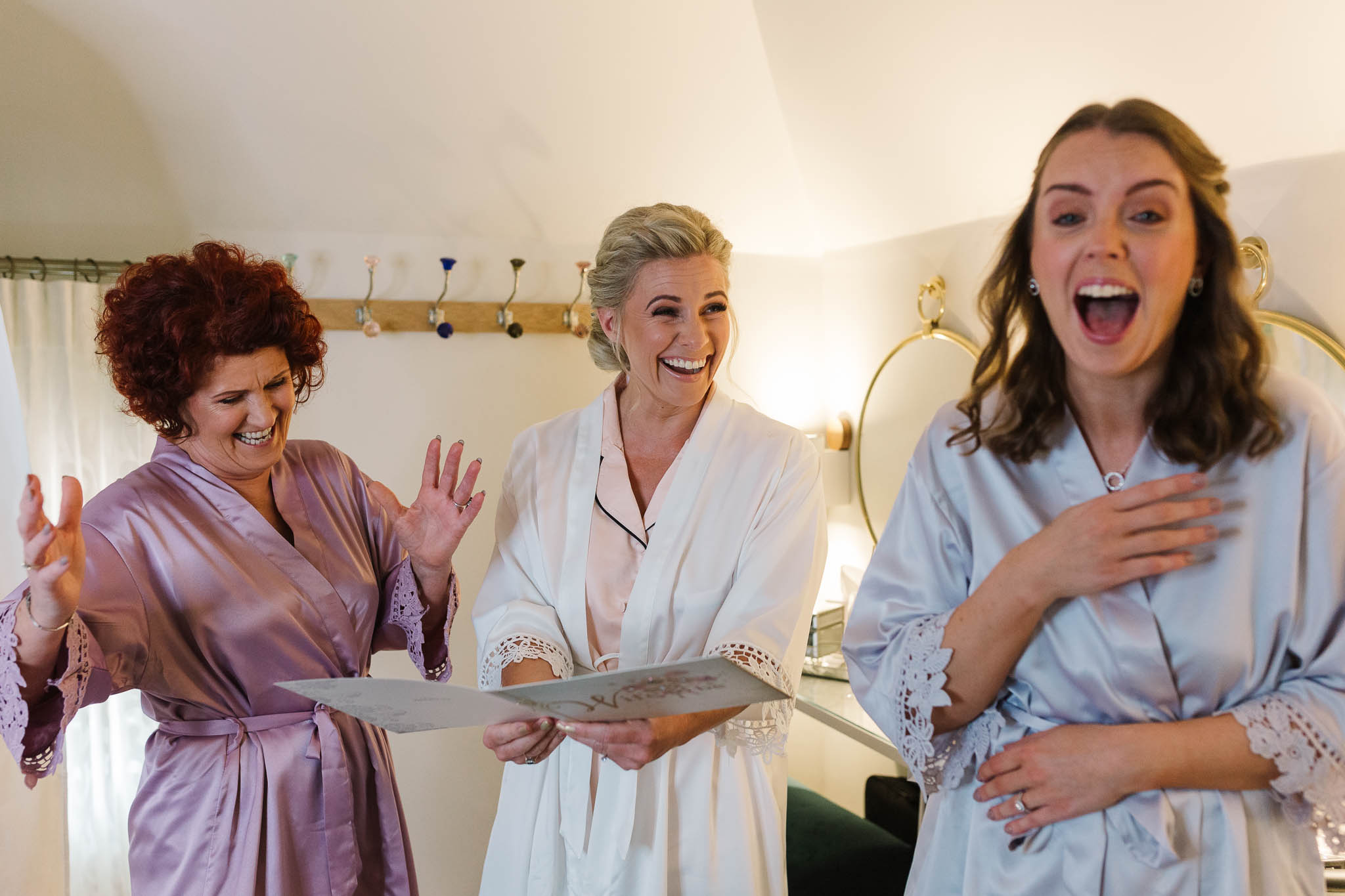bride and bridesmaids laughing at card