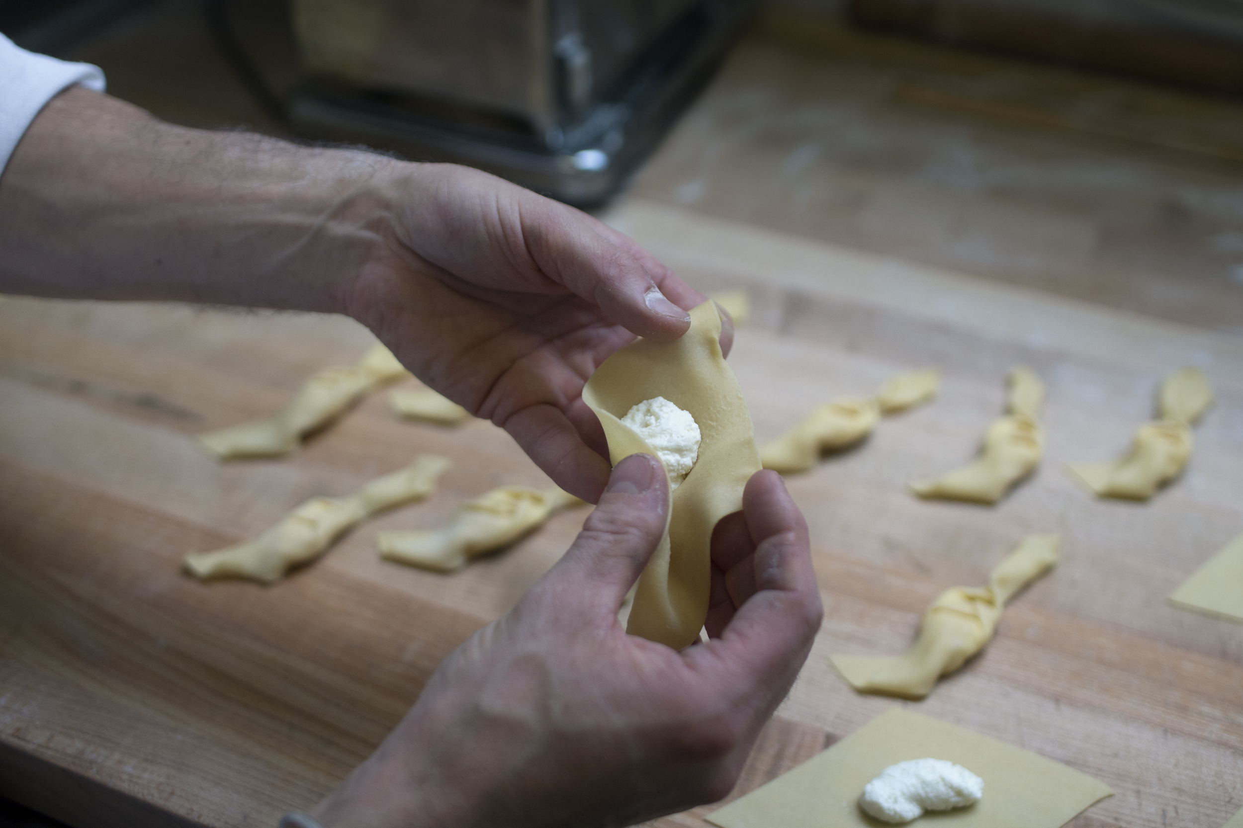 head baker peter endriss shaping fresh pasta dough into braided ricotta ravioli