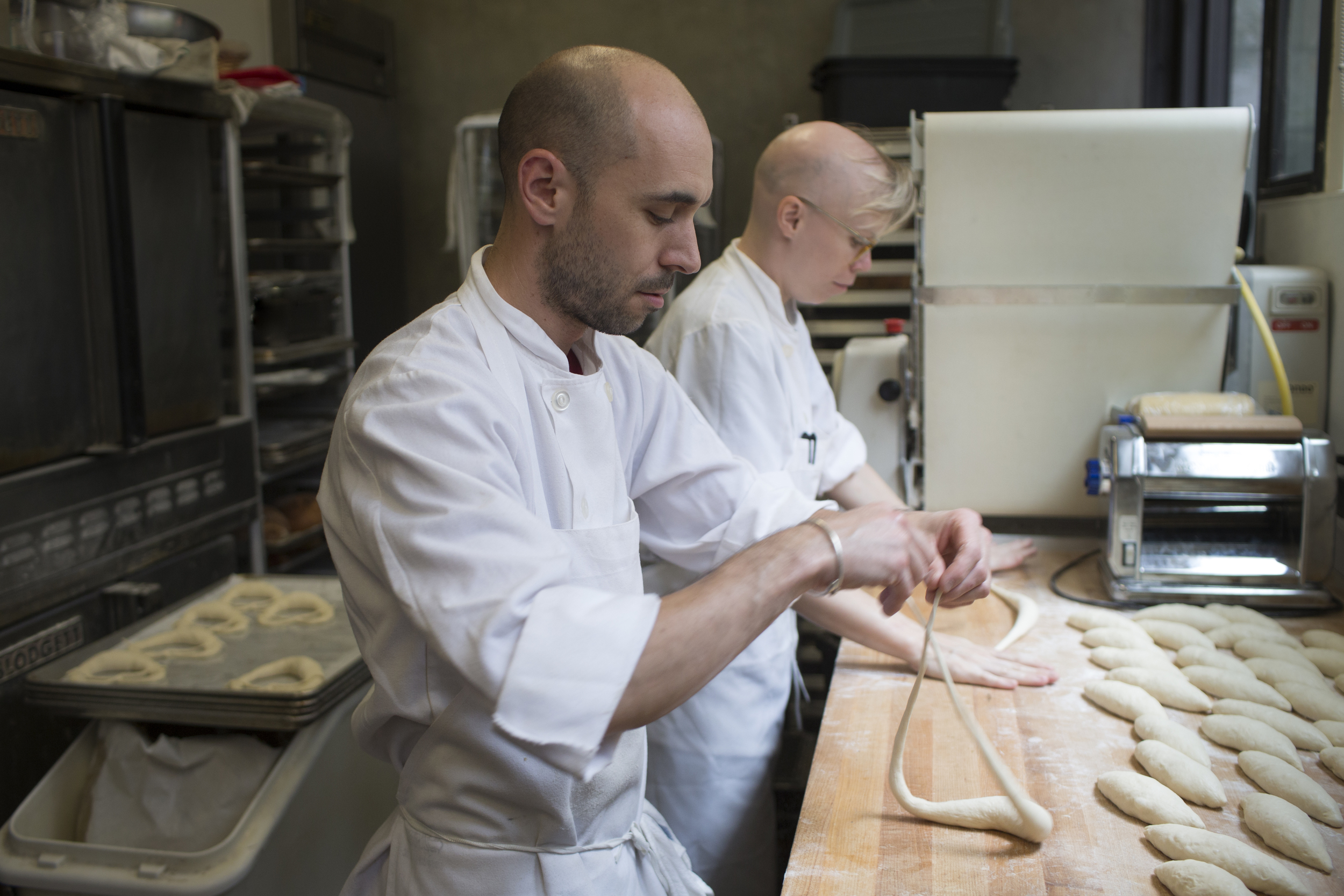 head baker peter endriss shaping pretzels with another baker in the runner and stone bakery