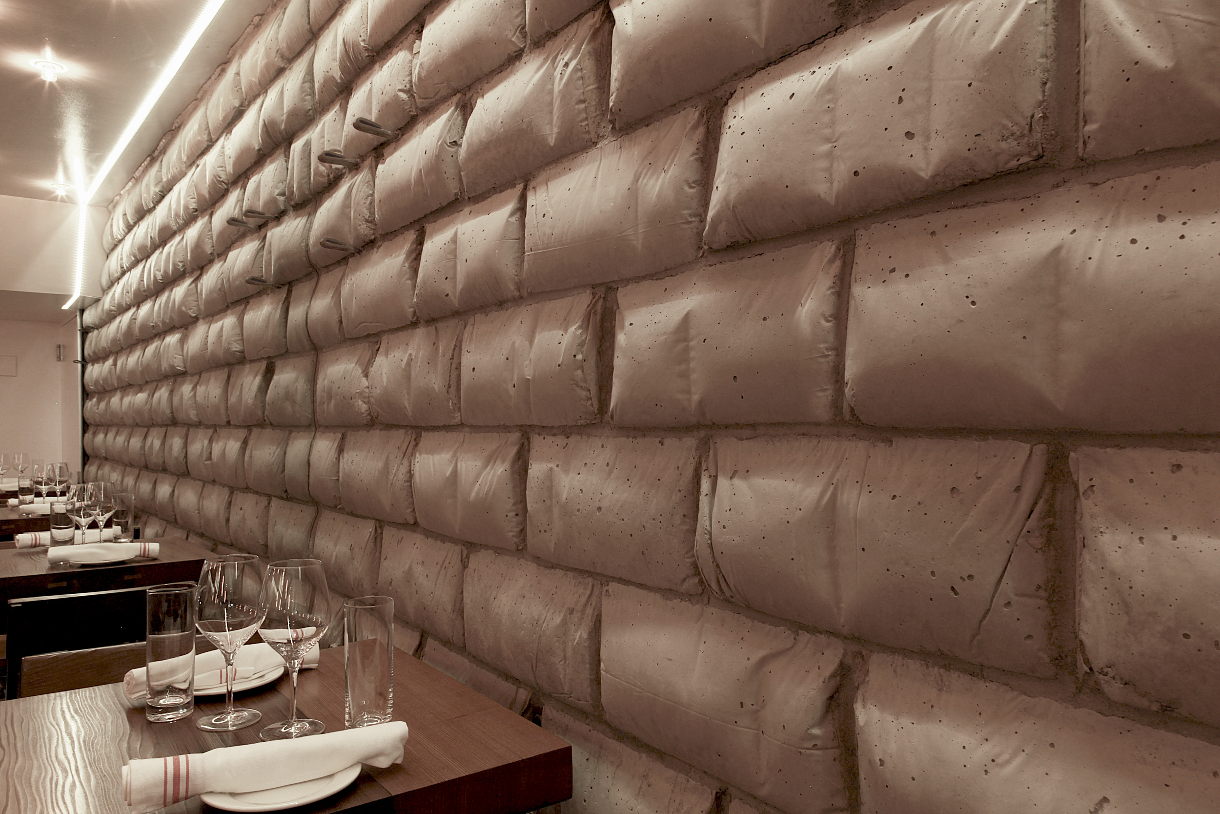 the interior wall at runner and stone showing concrete masonry units ("belly blocks") formed in flour bags, giving them the look of soft pillows