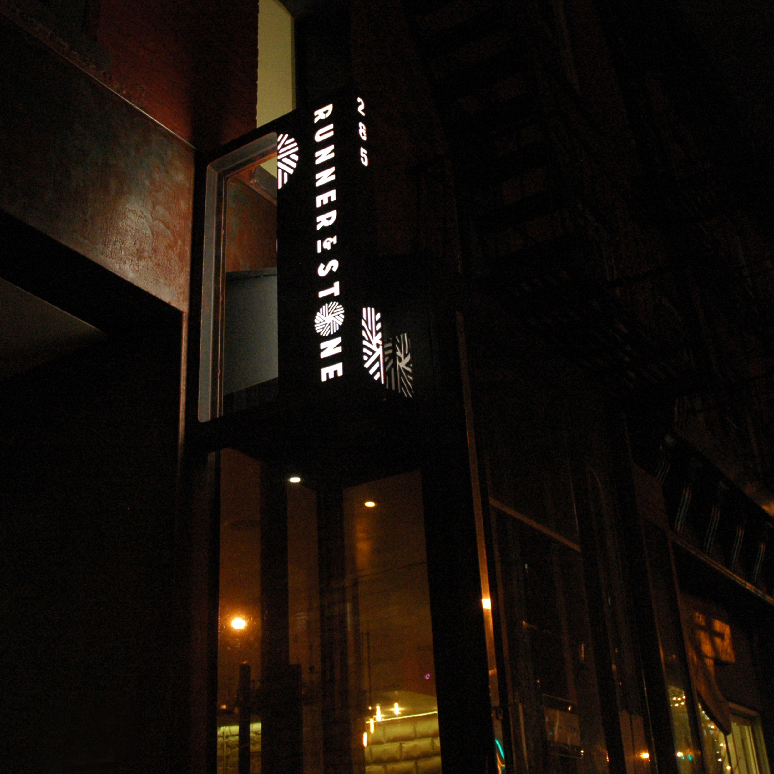 the illuminated exterior, punched steel storefront sign on the runner and stone facade