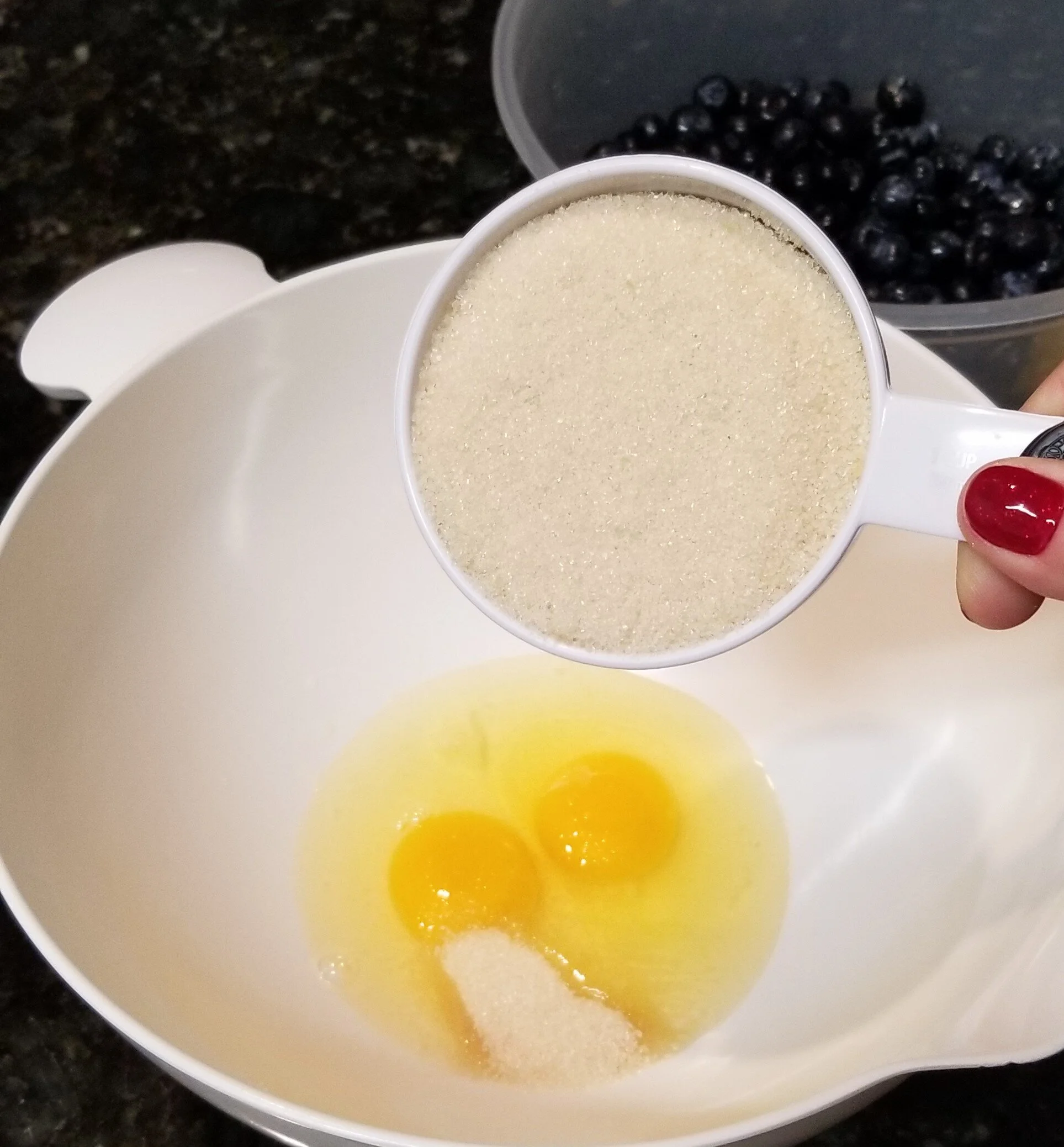 Adding sugar to a white bowl with 2 eggs