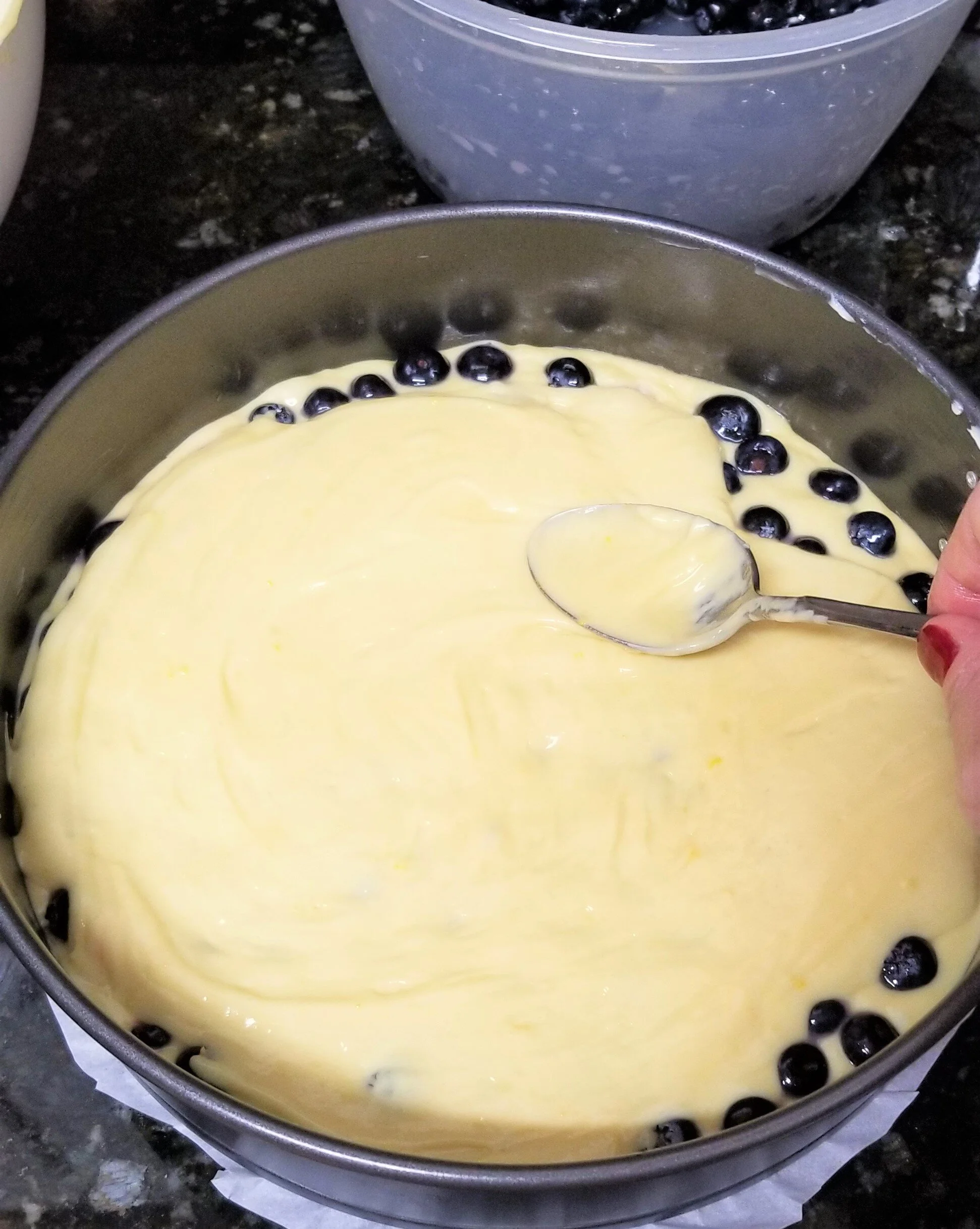 Adding cake batter into a spring form with blueberries 