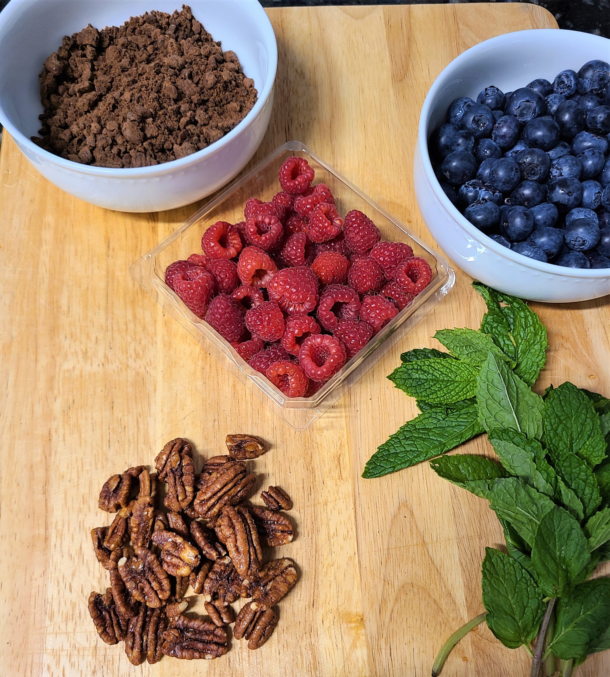 teddy grahams, blueberries, raspberries, mint on a wooden cutting board