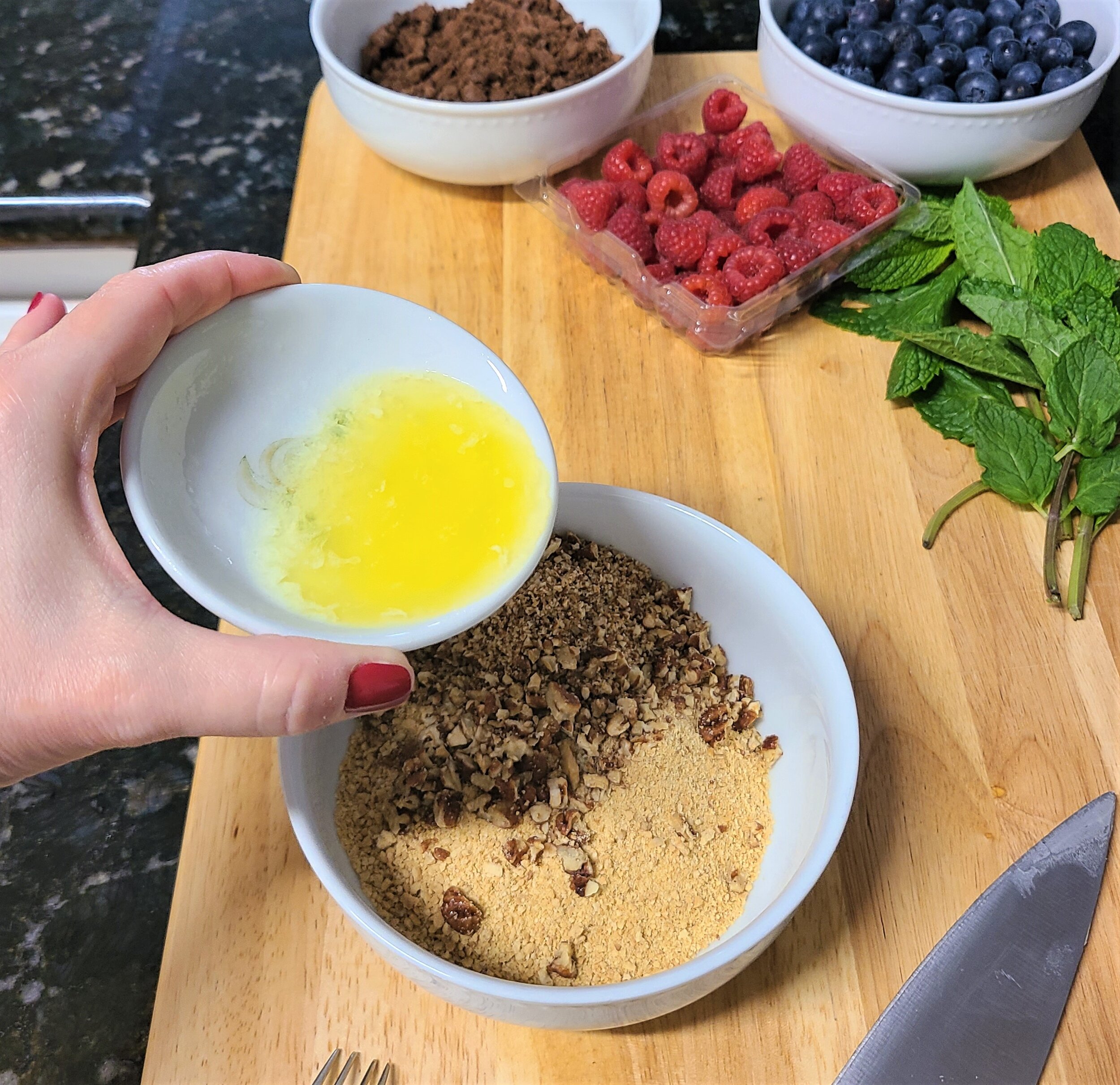 adding melted butter to crushed almonds and graham crackers