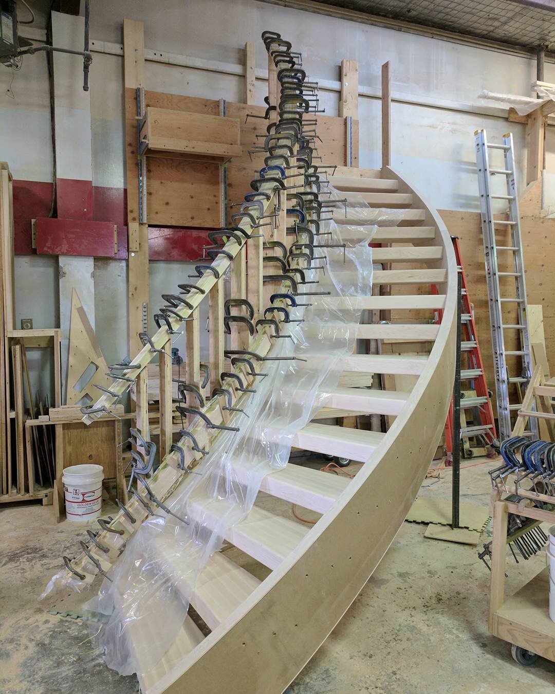 Lots of bending on this curved stair! This one has a custom curved half wall attached to the inside of the curve. Super fun to build curves again! #bpbanister #stairs #railings #yxe #curvedstairs #customwoodwork #customstairs