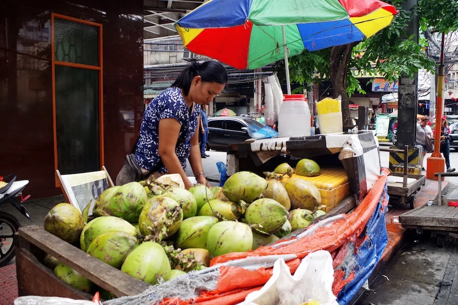 A mother selling drinking coconuts in Manila. Photo by Alee Catagatan.