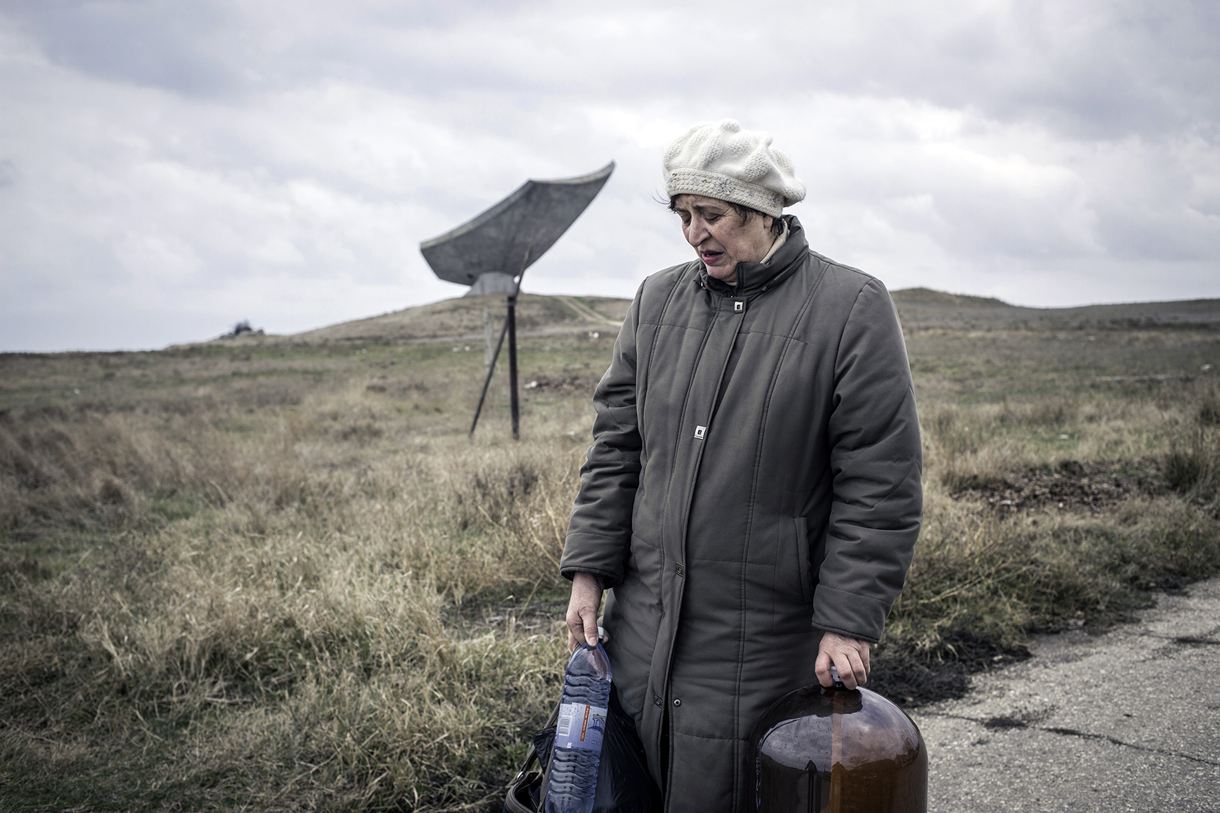 Woman in a village near Kerch, carrying home canisters with drinking water, Crimea, 2014