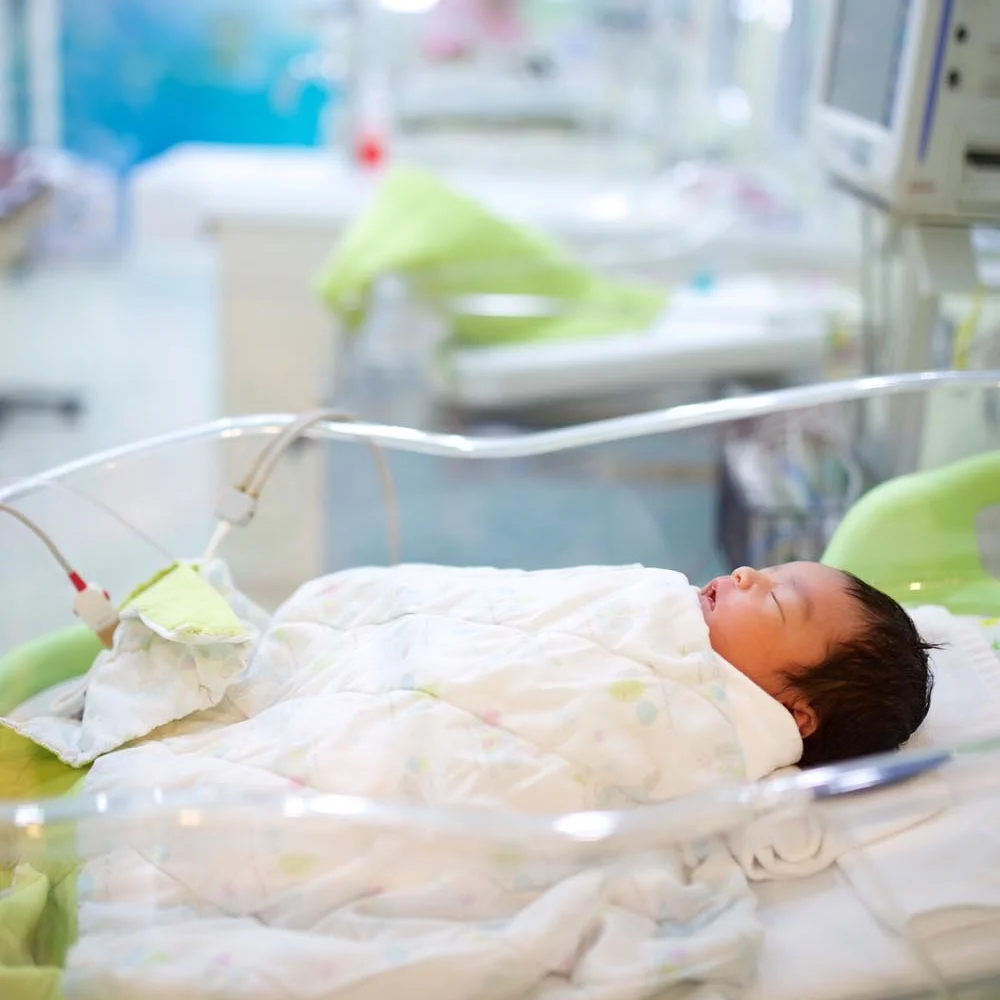 asian preemie baby laying supine in NICU bed