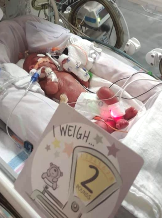 preemie with milestone card in nicu.jpg