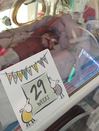 preemie with milestone card in nicu 2.jpg