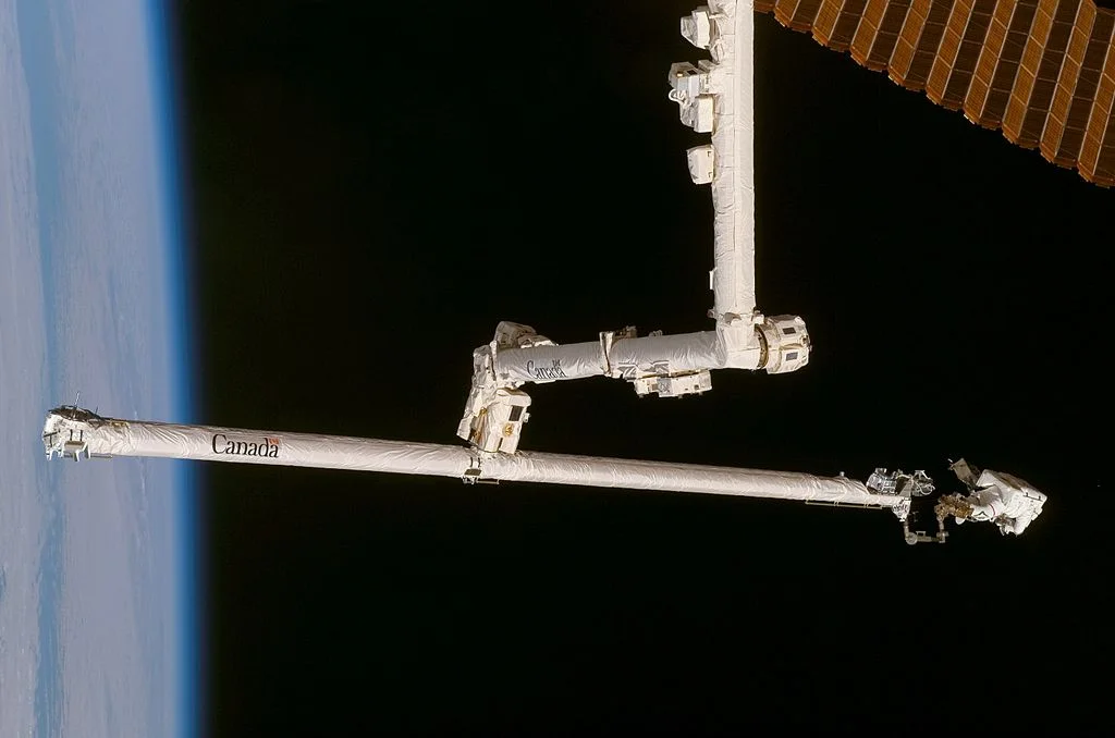 Scott Parazynski on the end of OBSS, being gripped by Canadarm2