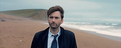 Serious David Tennant on a windswept beach.
