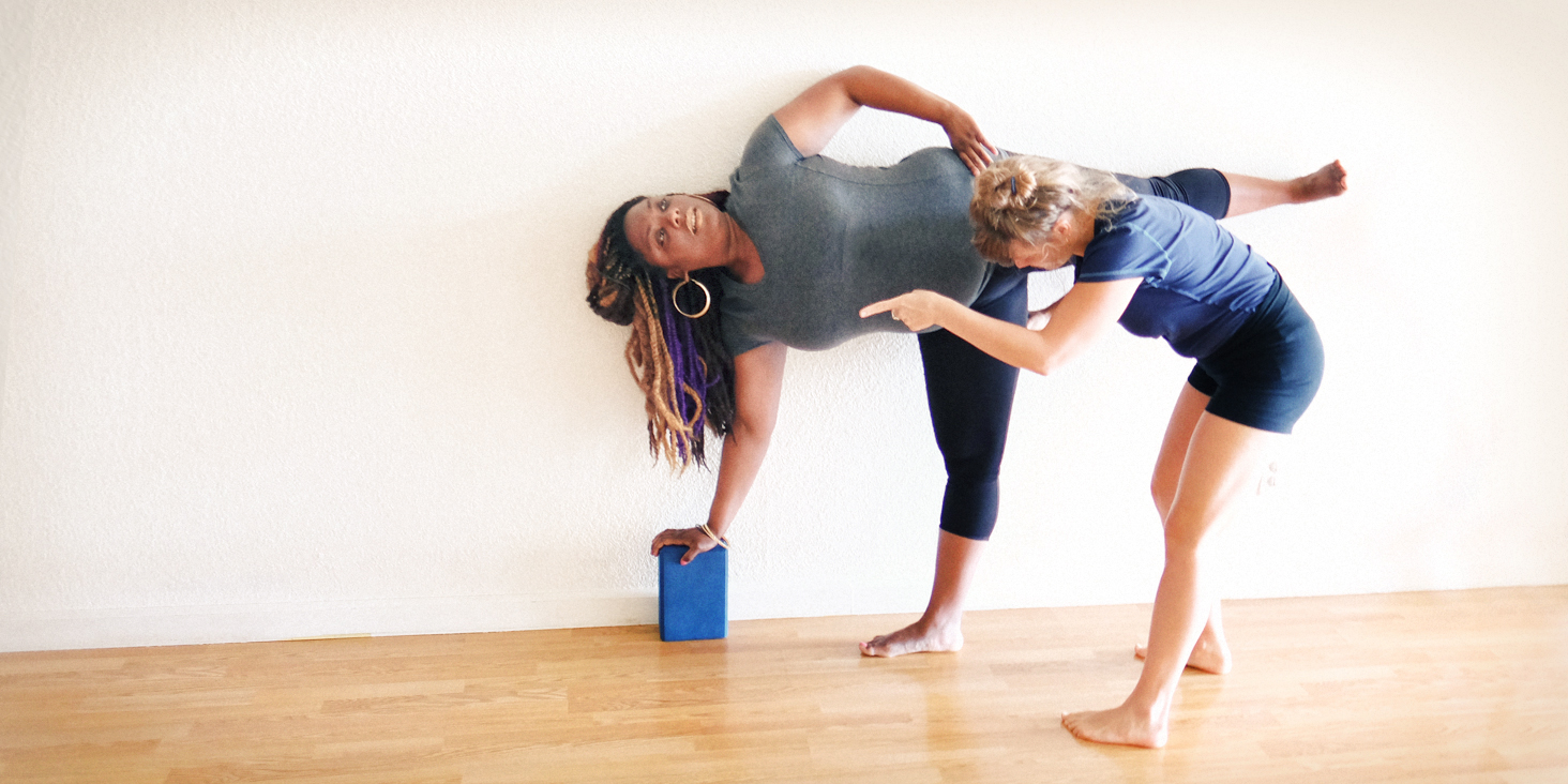 Anneke guides a student in Ardha Chandrasana, a wonderful asana for alleviating menstrual cramps. Photo credit: Kara Cooper