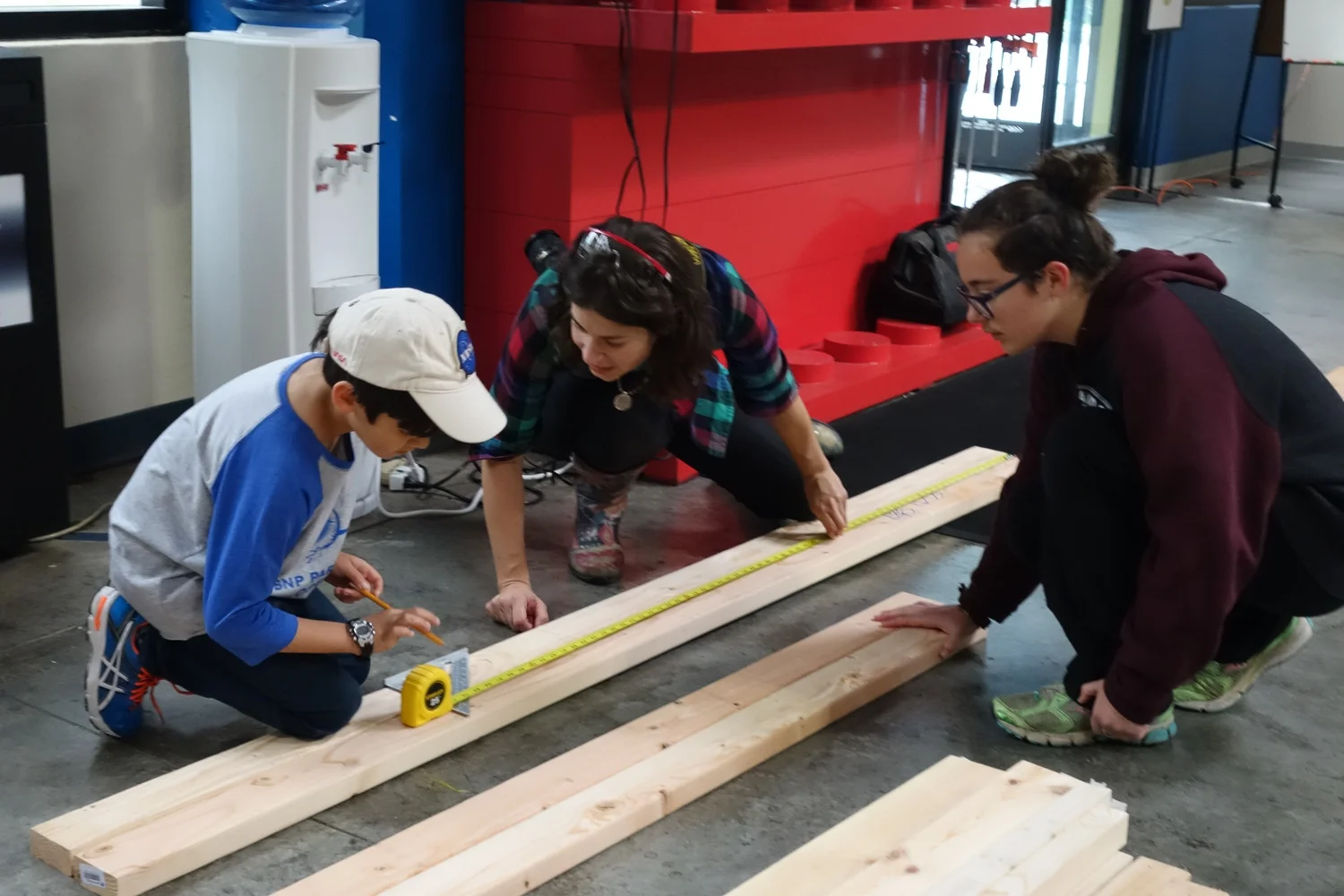 Katie shows Robert how to use a speed square to mark his cut.