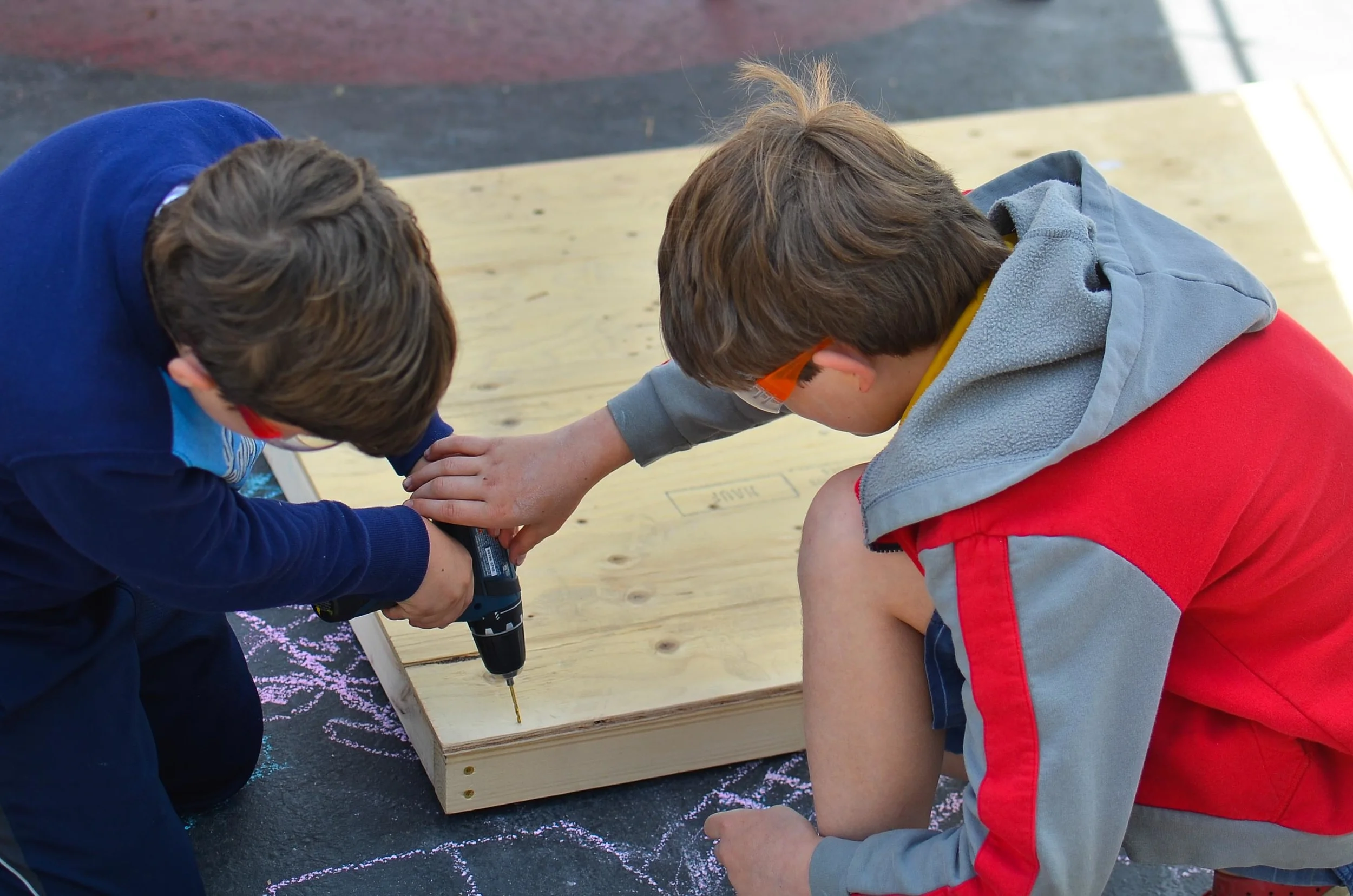 Dante helps Dr. Elliot make sure his drill is perpendicular to the wood. 