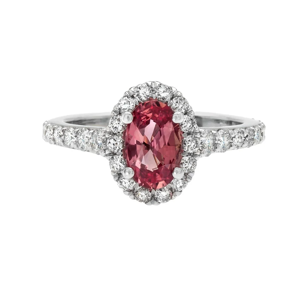 1.15 carat Oval Cut Padparadscha Sapphire Ring. 0.88 carats of round brilliant cut Diamonds surround the center stone. Set in platinum.