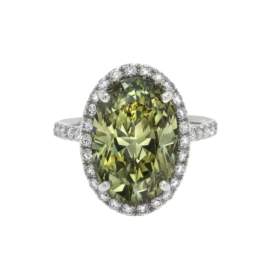 6.94 carat Fancy Deep Greenish/Yellow Oval Diamond Halo Ring. 0.94 carats of Round Brilliant Cut Diamonds surround the center stone. Set in platinum.