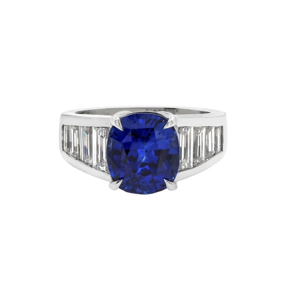 4.81 carat Oval Cut Sapphire. Surrounding the center stone are 1.79 carats of tapering Diamond Baguettes. Set in platinum. 
