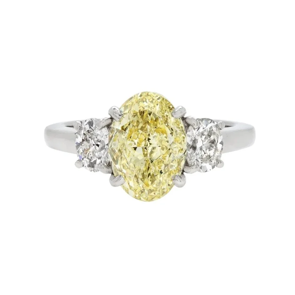 3.05 carat Oval Cut Fancy Yellow Diamond 3-stone Ring. 0.80 carats of Oval Cut Diamonds surround the center stone. 3.85 carat total weight. Set in platinum.