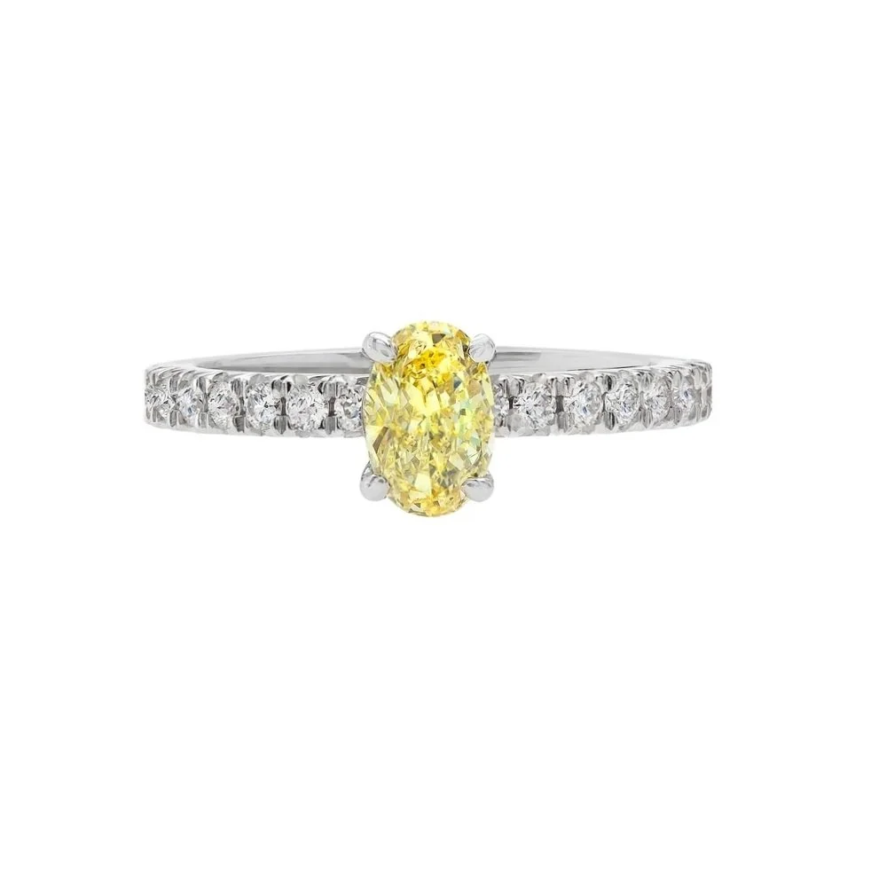 0.66 carat Fancy Intense Yellow Oval Cut Diamond Ring. Surrounding the center stone are 0.64 carats of Round Brilliant Cut Diamonds. Set in platinum.