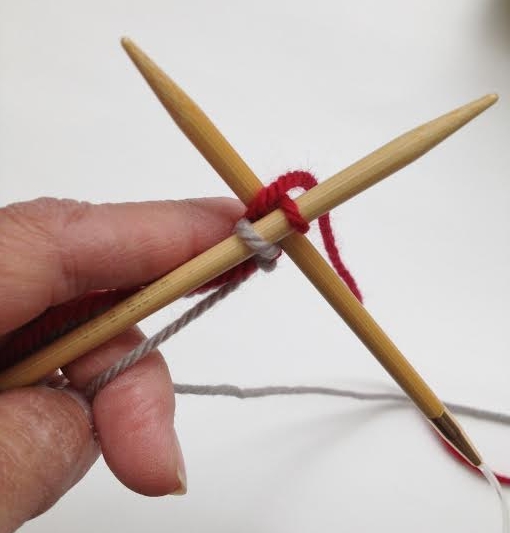1. Insert the tip of the right needle between those 1st 2 stitches, wrap the main color yarn and draw thru a loop.