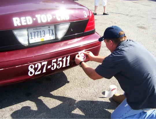 Building local recognition has been key to fostering NIOT's message. Here, a Bloomington-Normal cabbie installs a Not In Our Town decal.