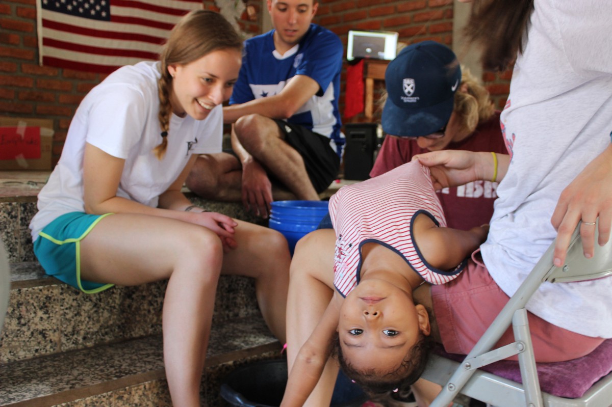 Natalie Duda washes the feet and puts shoes on a child from the community.