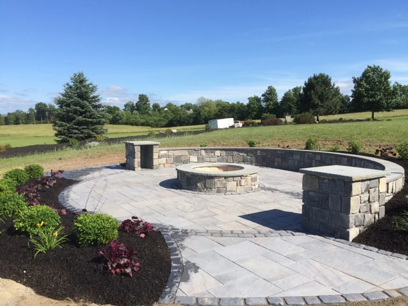 Landscape construction Syracuse NY paver patio with fire pit and stone seating wall