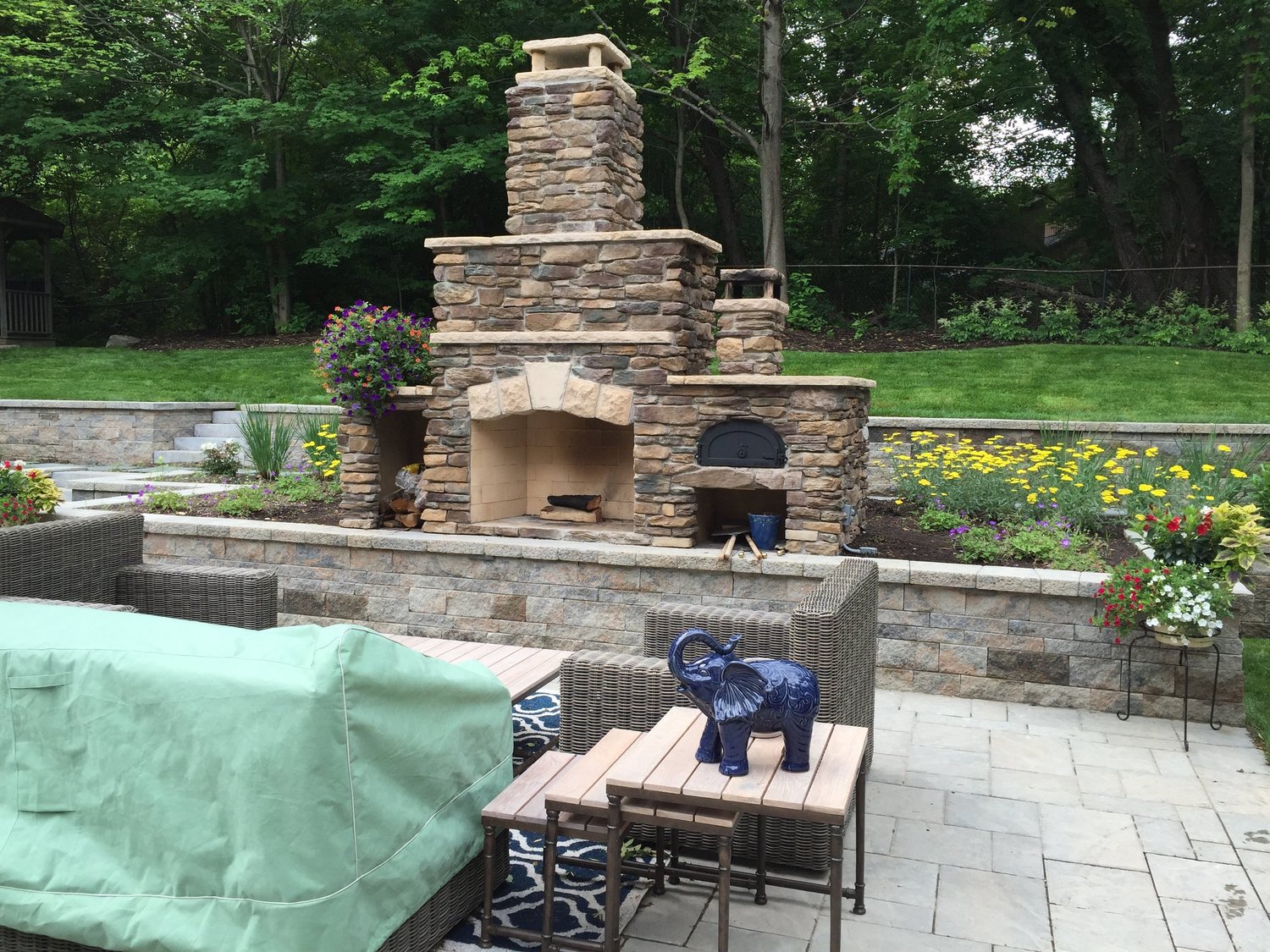 Custom outdoor fireplace in Central NY with double-tiered stone chimney and keystone arch