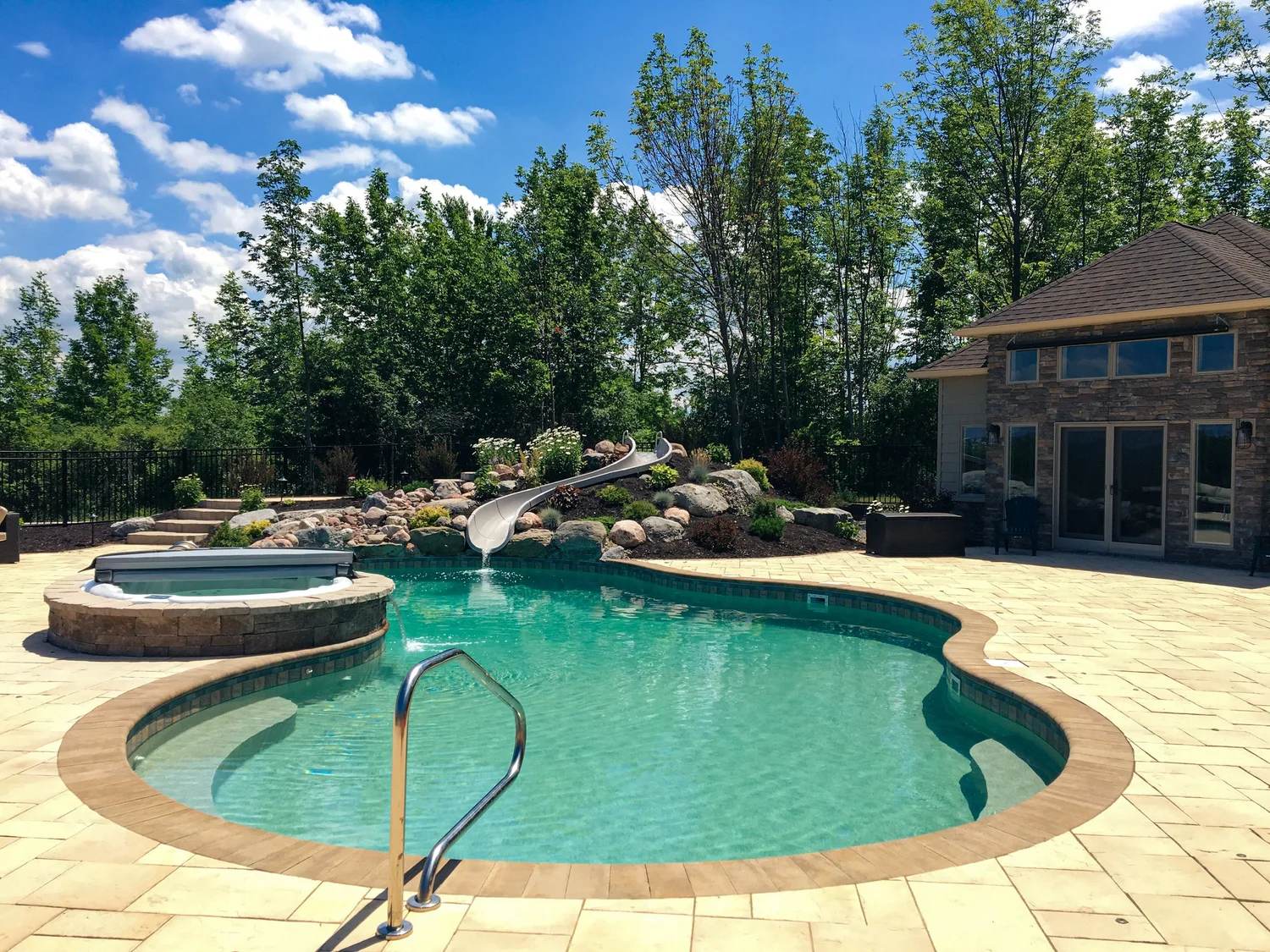 Lush landscaping, lawn and plantings around a pool patio in Central NY