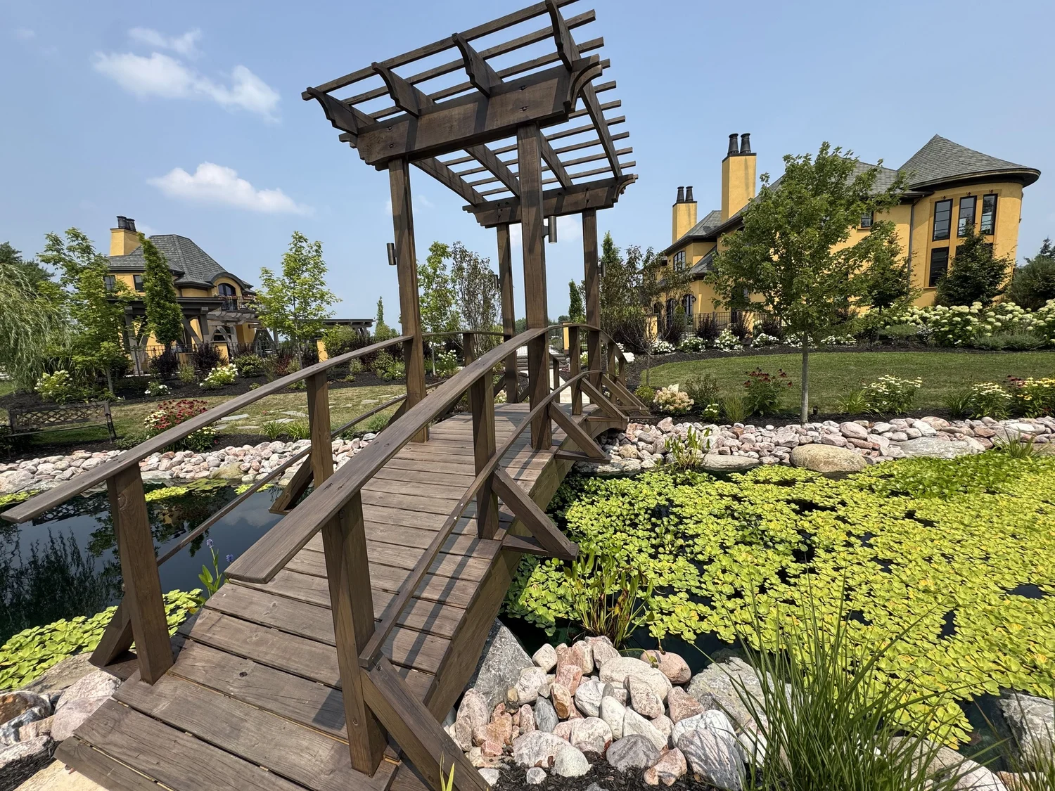 Koi pond installation Syracuse NY with wooden bridge, pergola and water plants