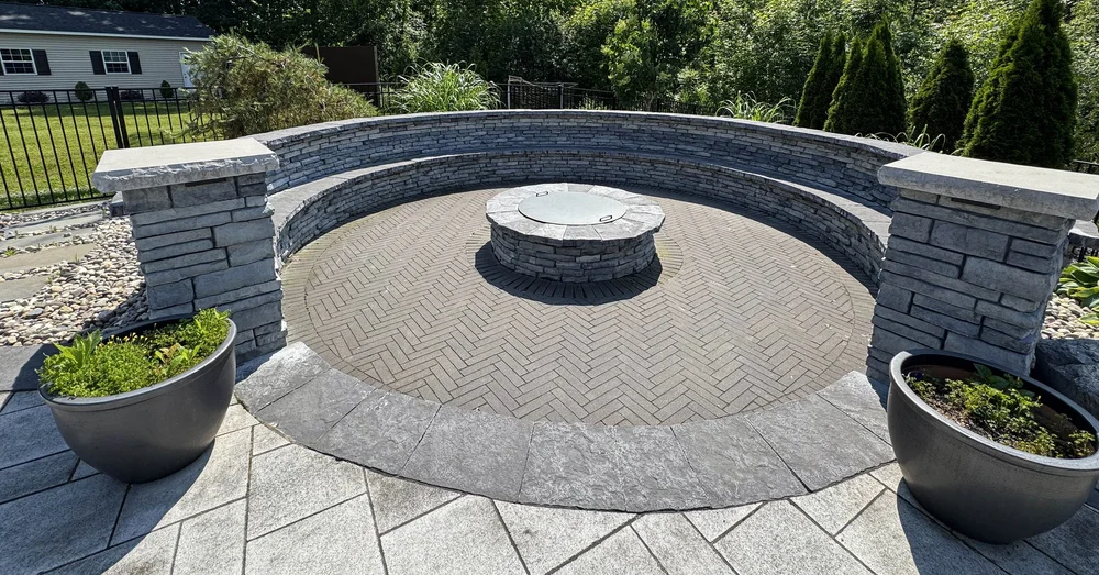 Paver patio installation in Syracuse NY with herringbone pavers, fire pit and seating wall