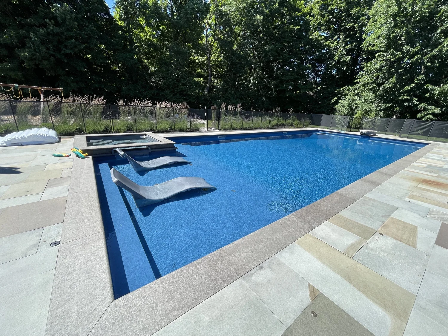 Pool design Syracuse rectangular in-ground pool with sun shelf and natural stone coping