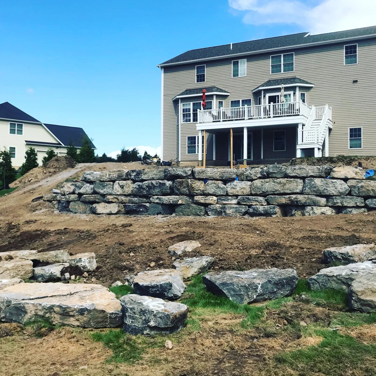 Boulder retaining wall terraces on a steep sloped backyard in Central NY