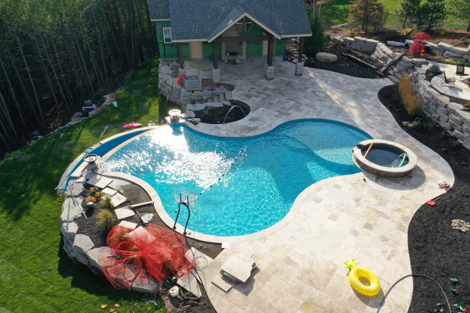 Pool with spillover spa, natural stone waterfall and paver deck in Central NY