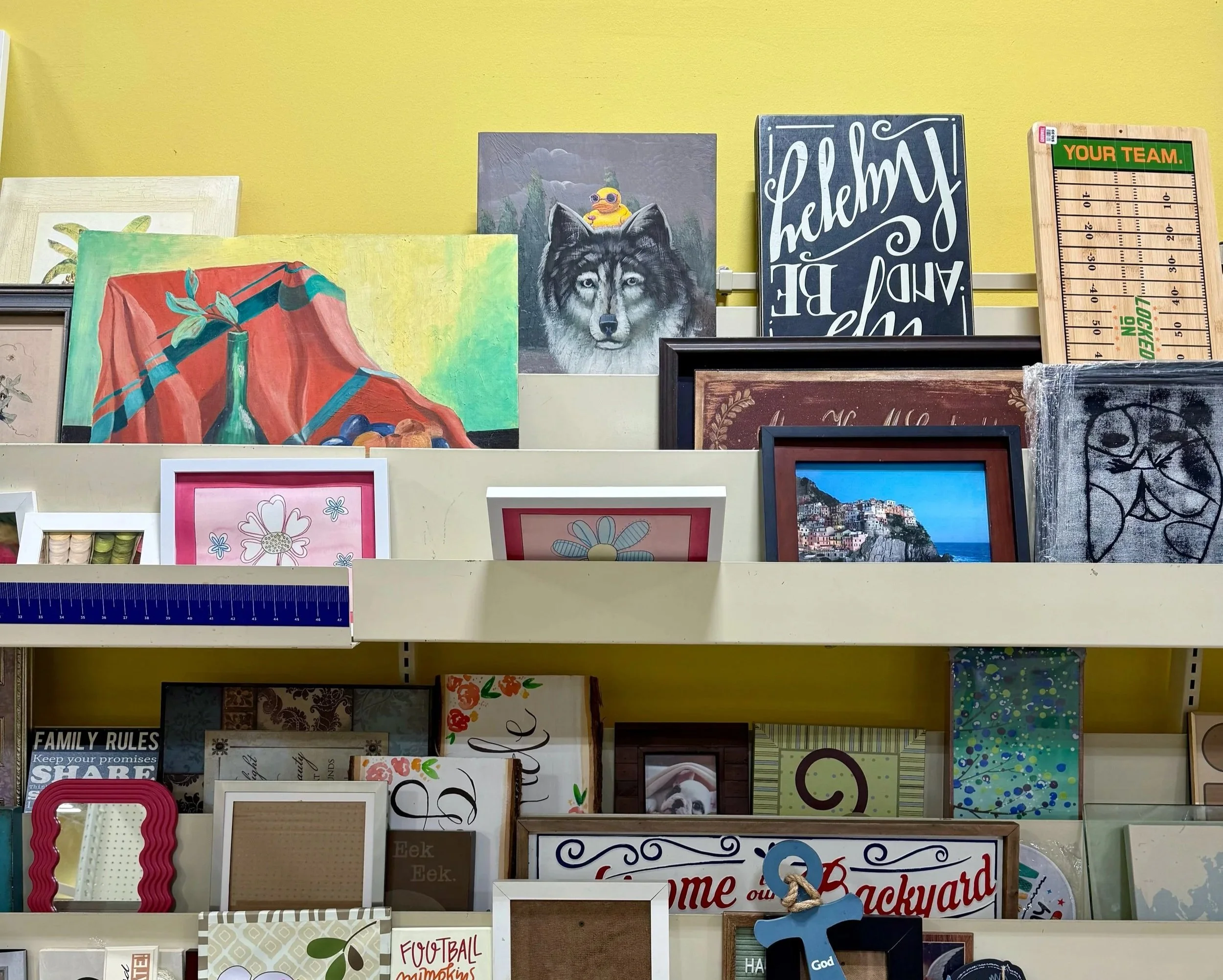 A variety of paintings and artwork stacked on a shelf