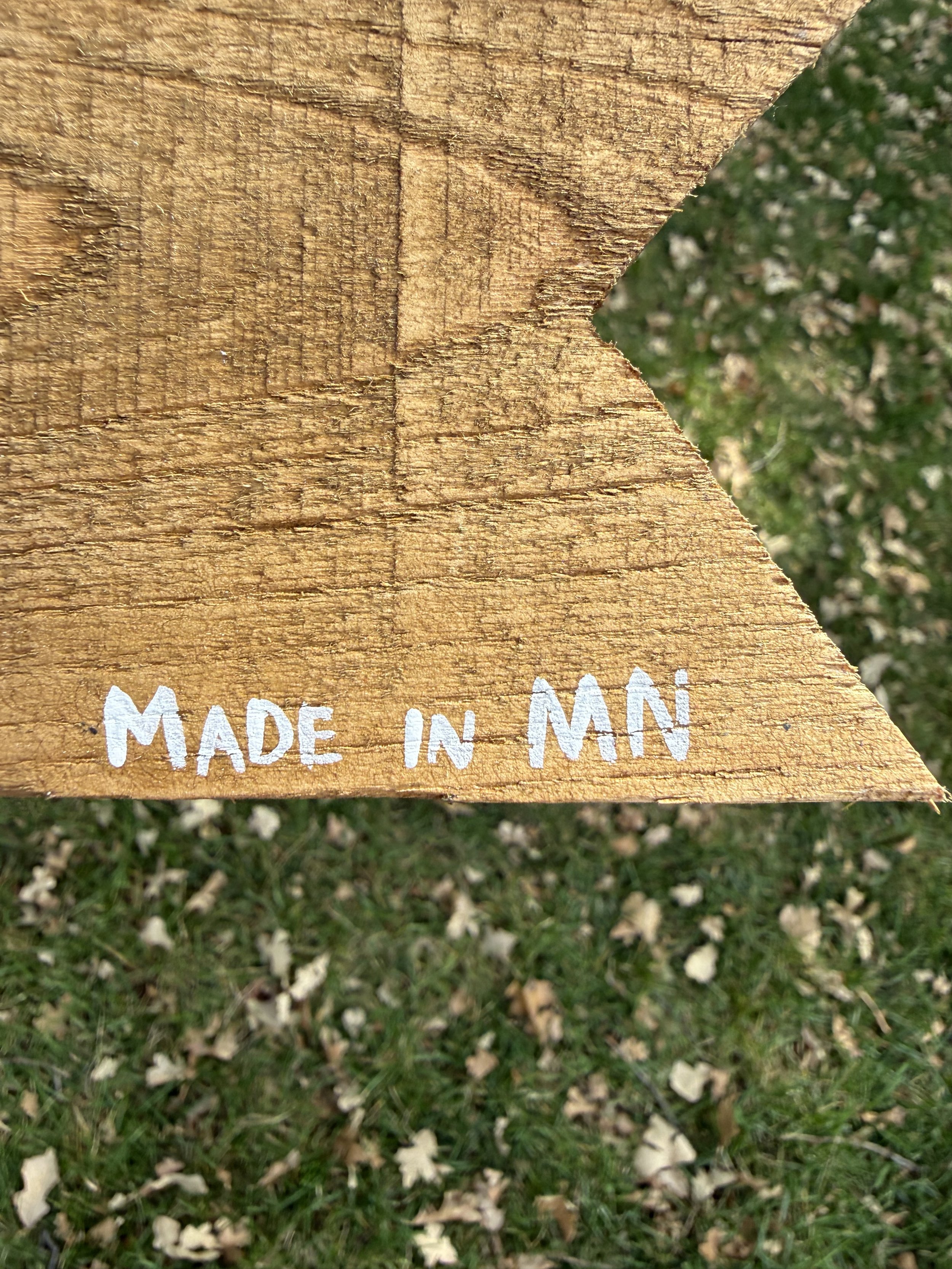 Detail of a piece of wood with words "Made in MN" painted on it.