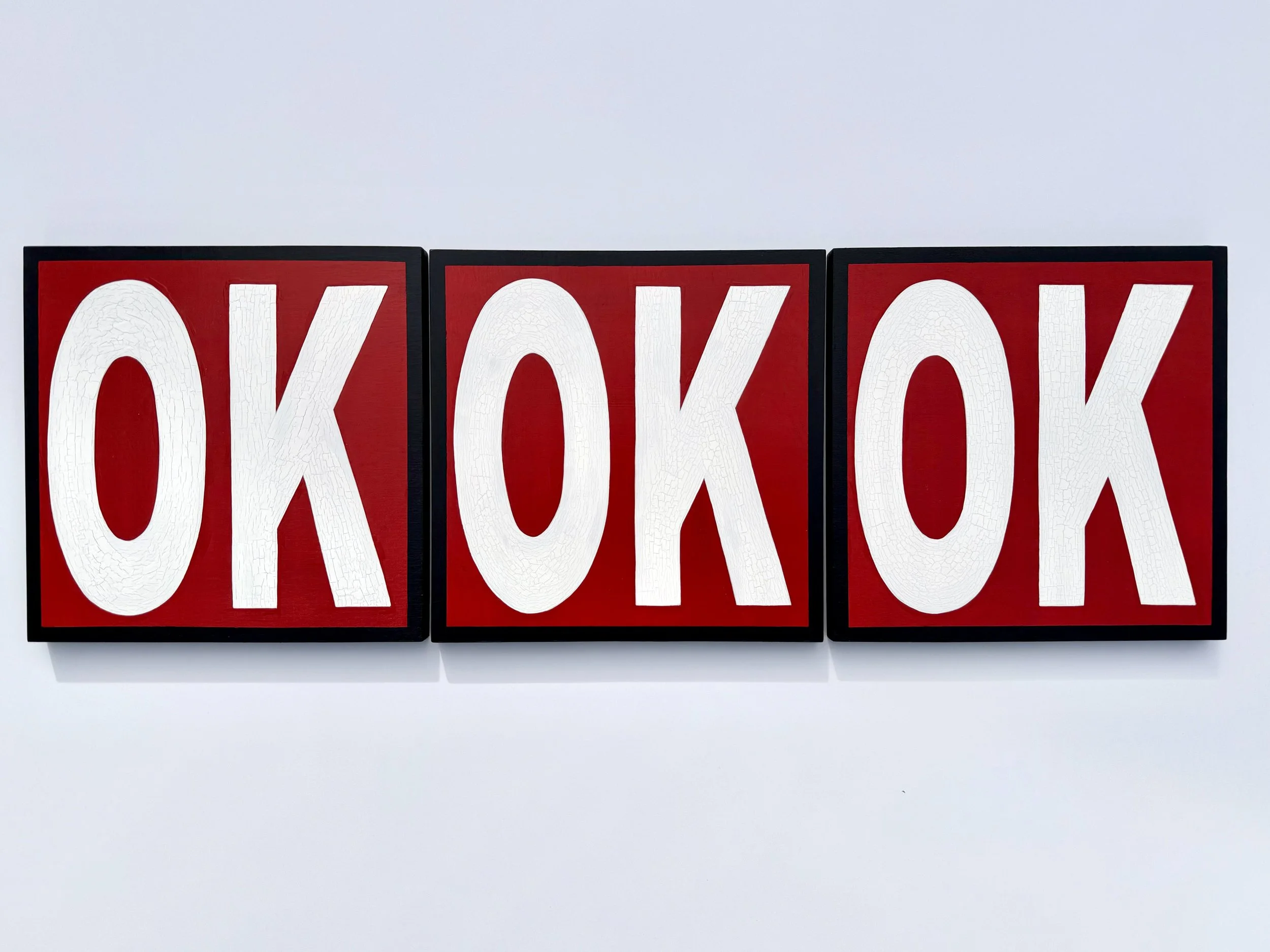 The word OK painted with white paint onto three red square panels