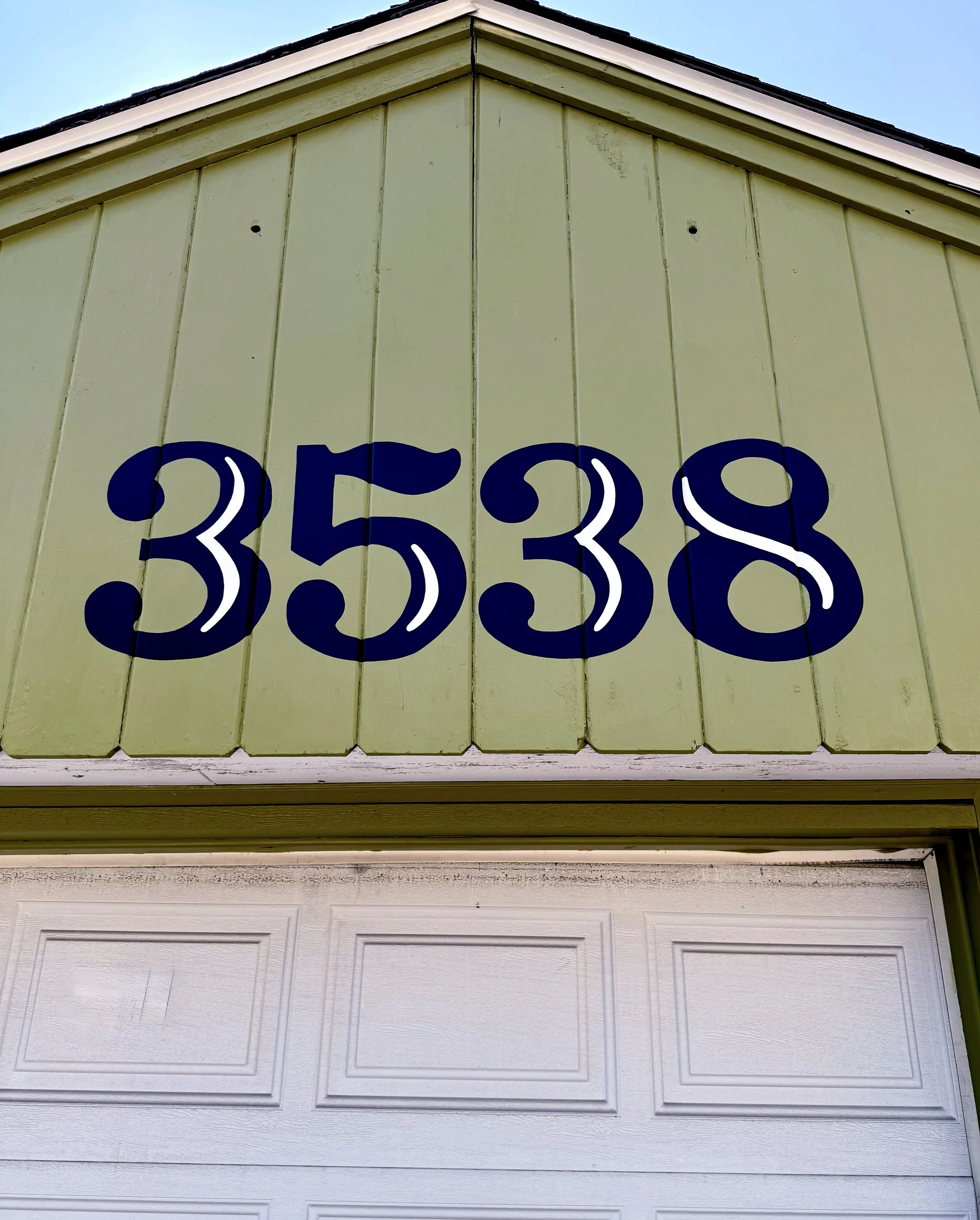 The number 3538 painted in black and white on a green wooden wall.