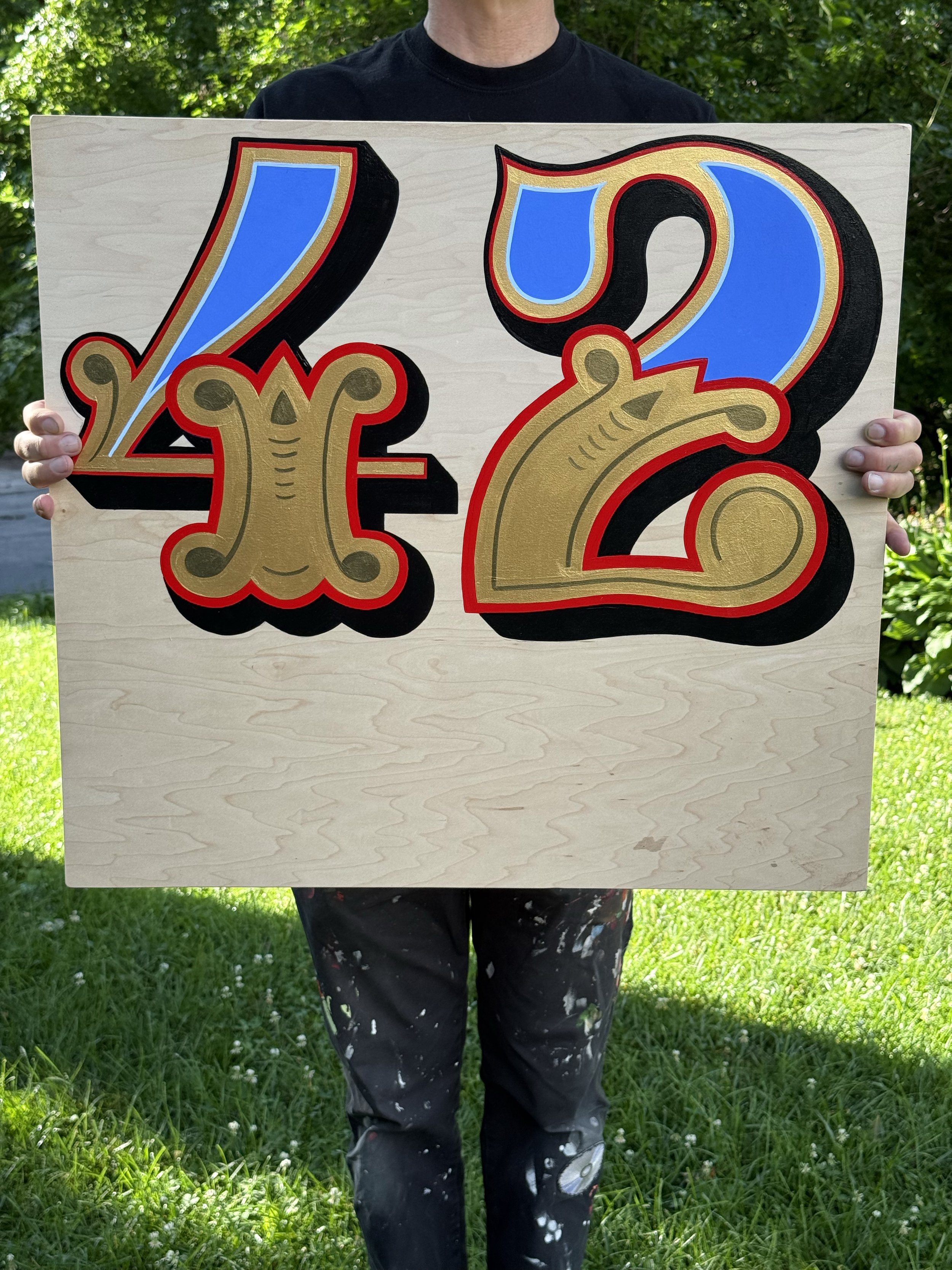 Person holding a piece of plywood with the number 42 painted on it.